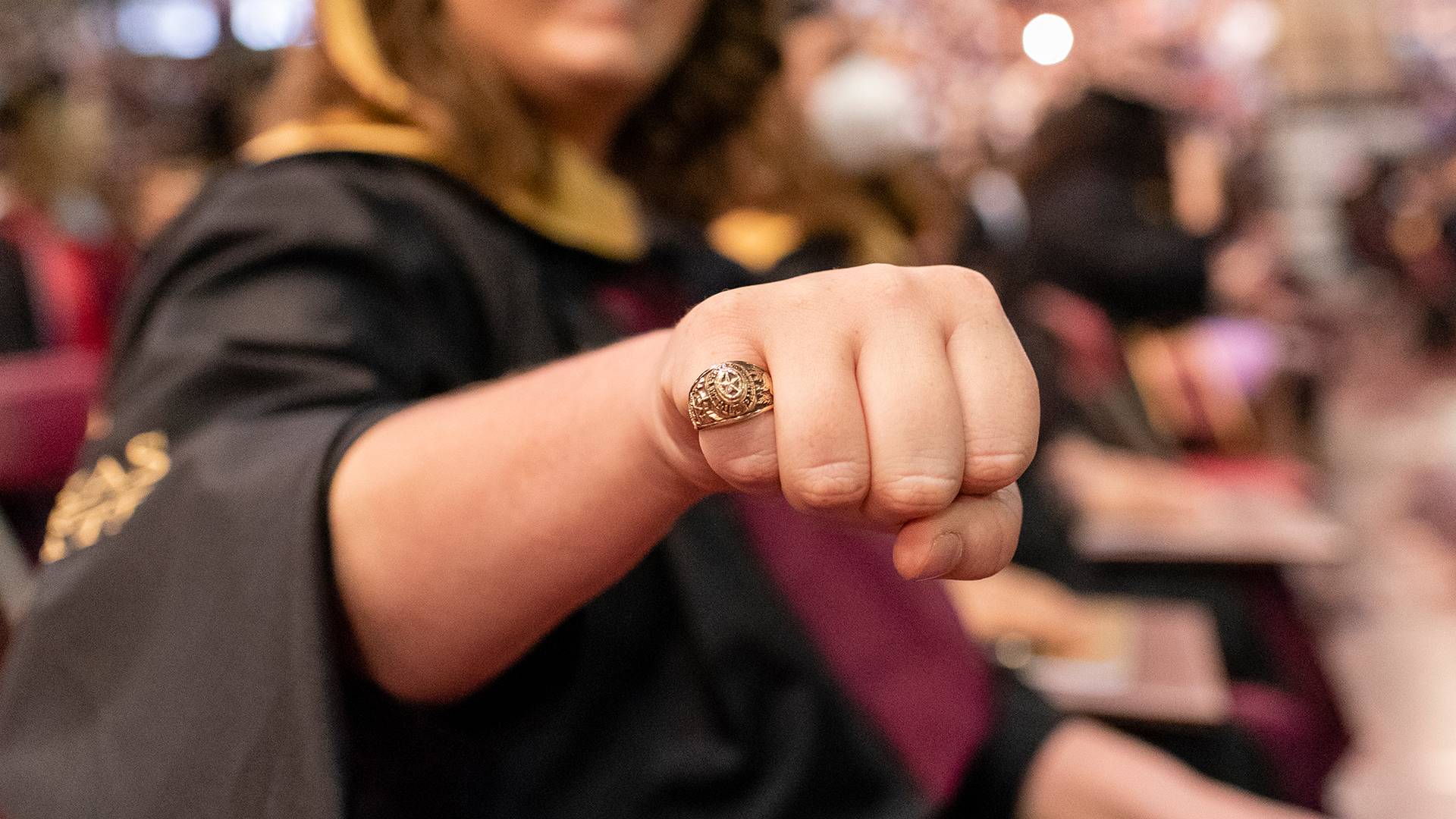 Student at commencement holding up hand with Texas State ring on their finger