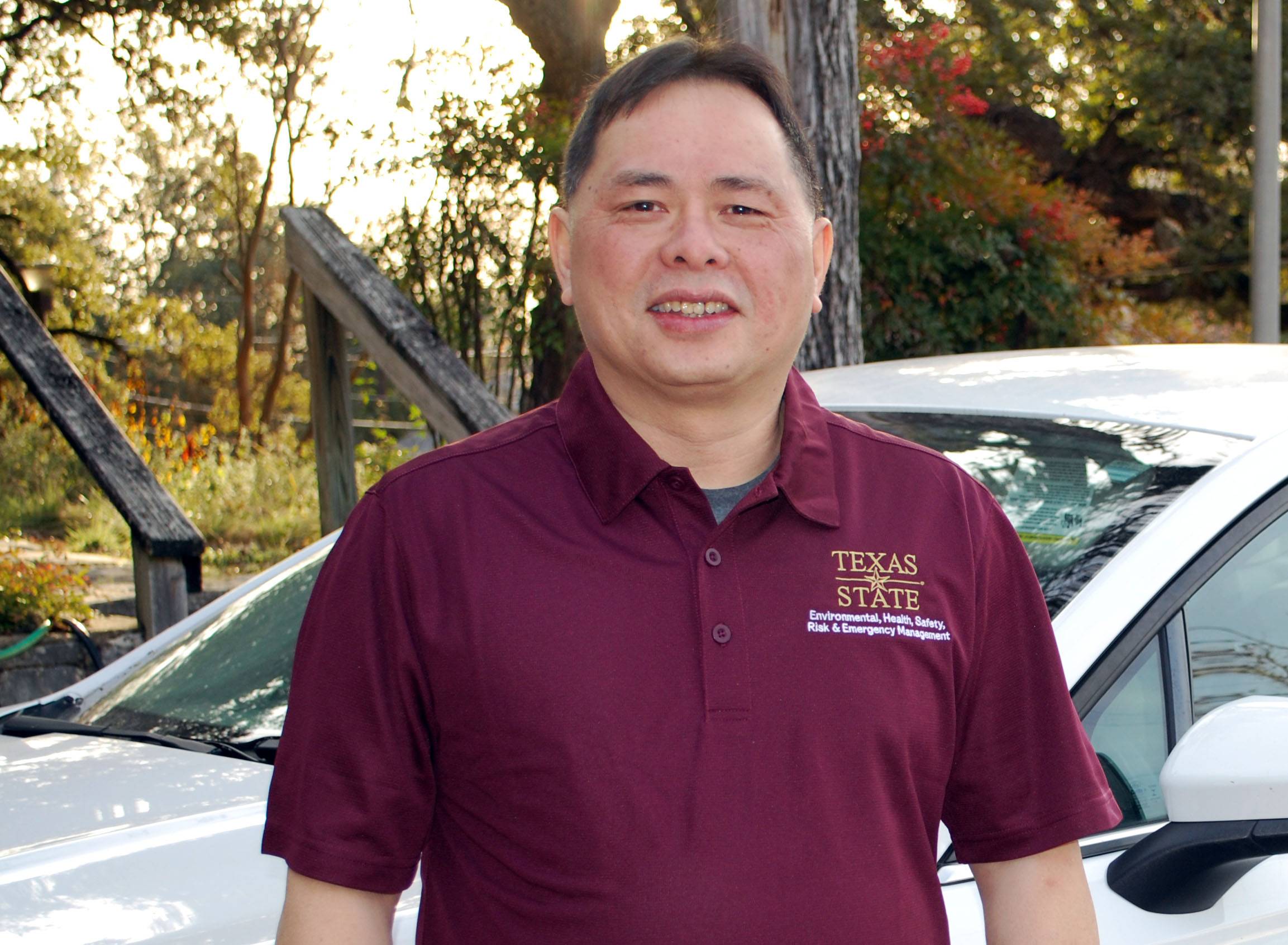 Quy standing in front of white car