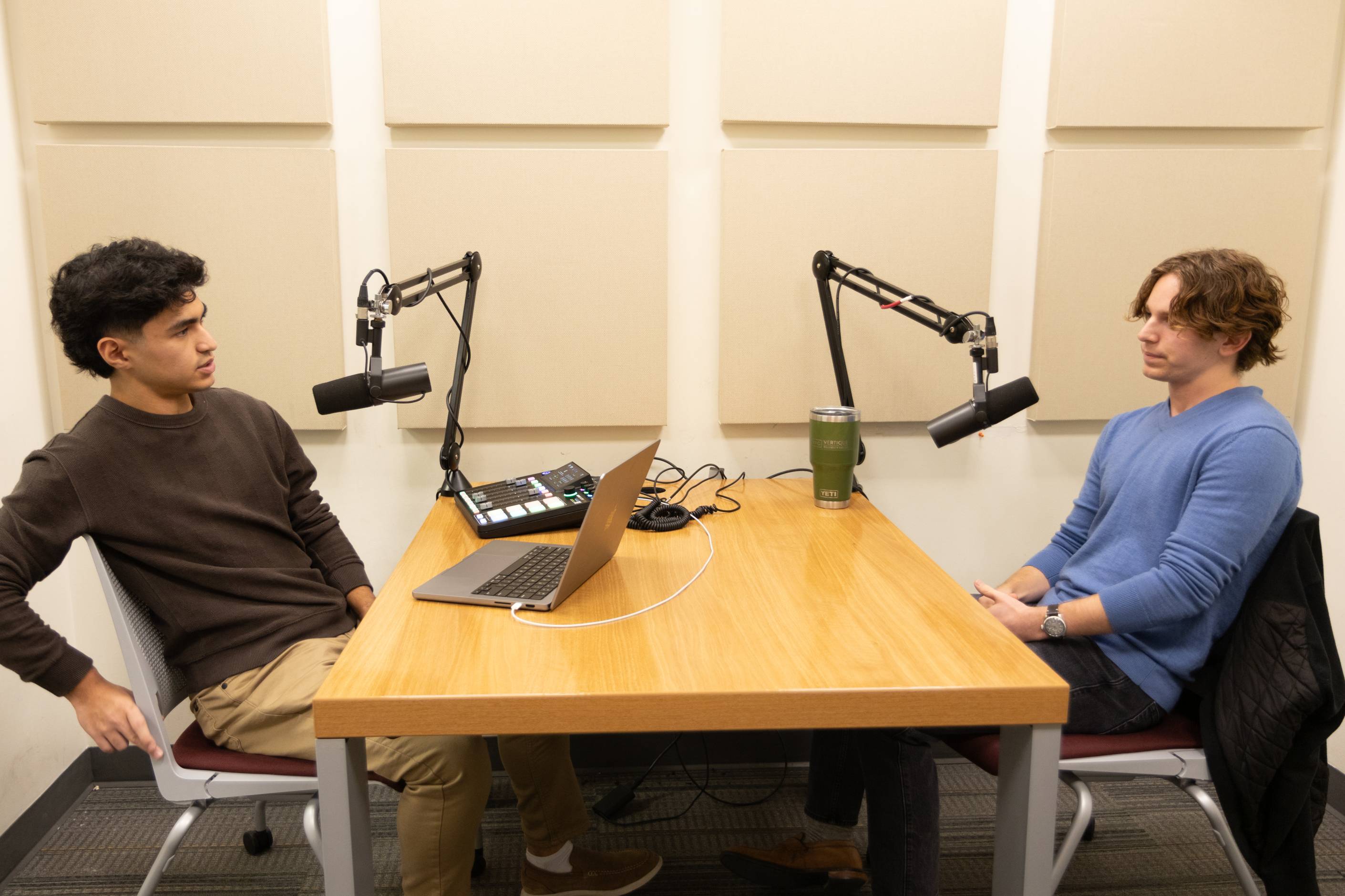 two boys sitting at a table over a podcast 