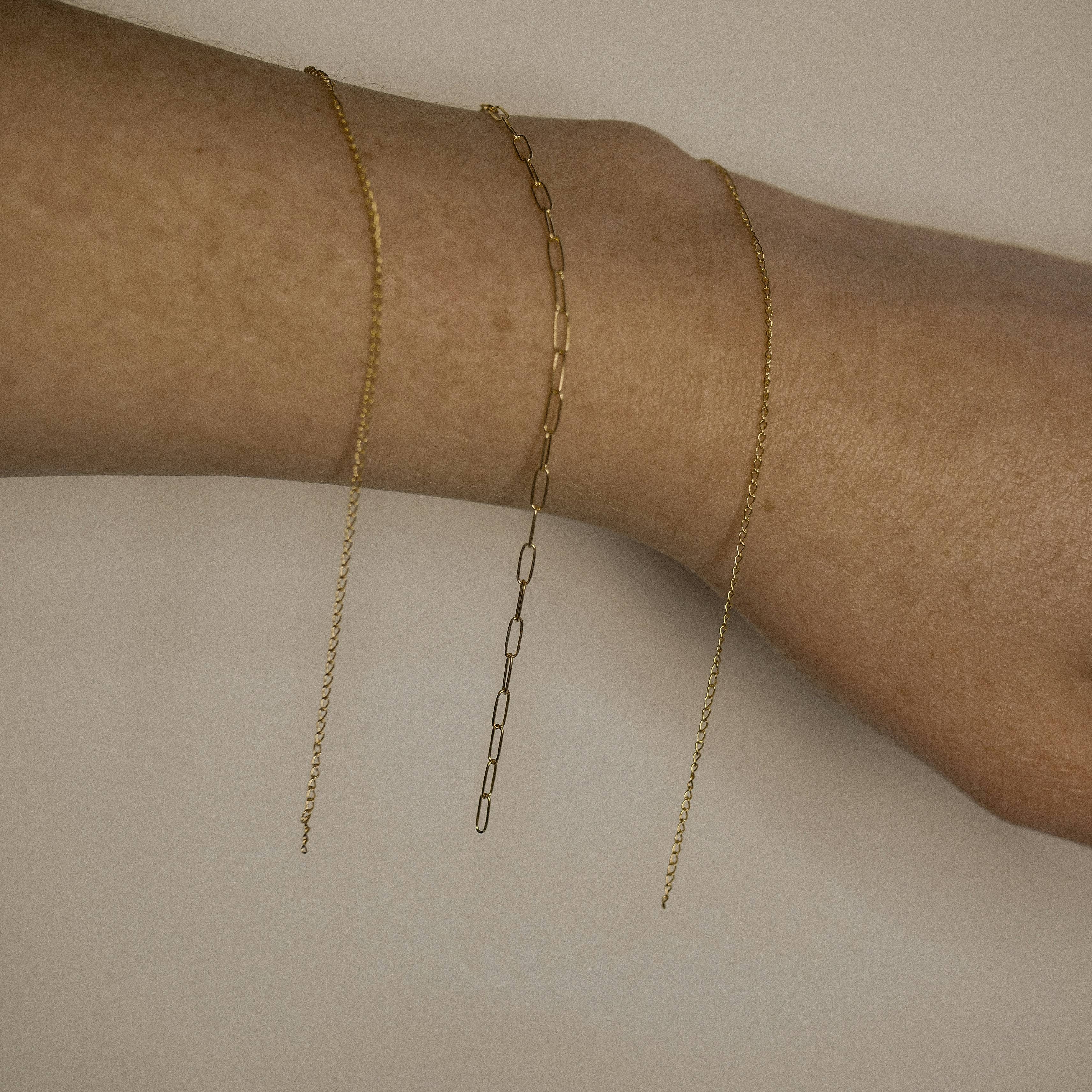 permanent jewelry with 3 gold bracelets on