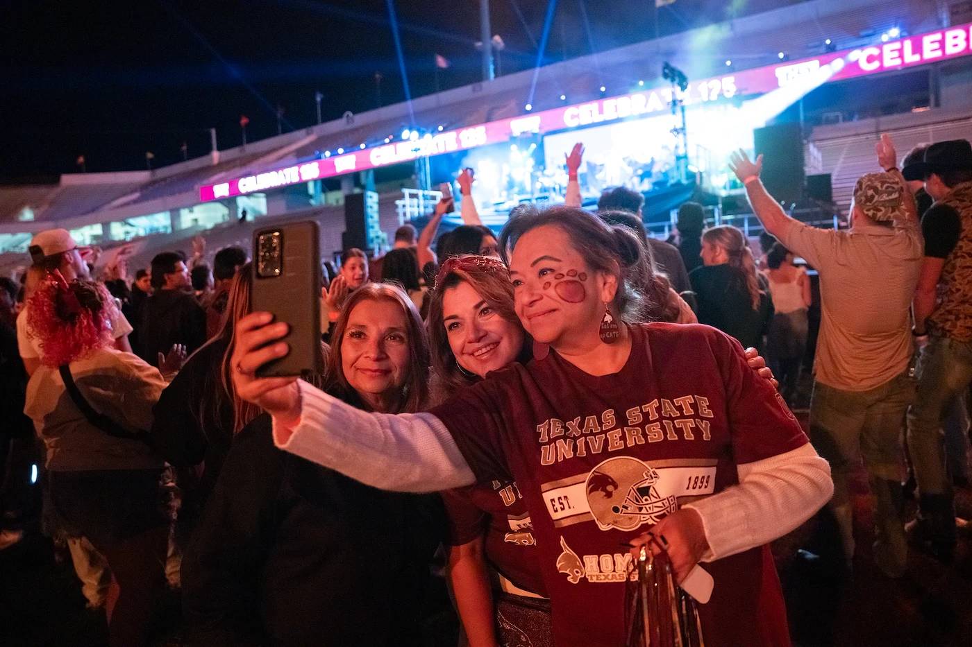 Girls taking a selfie in a crowd with face paint on