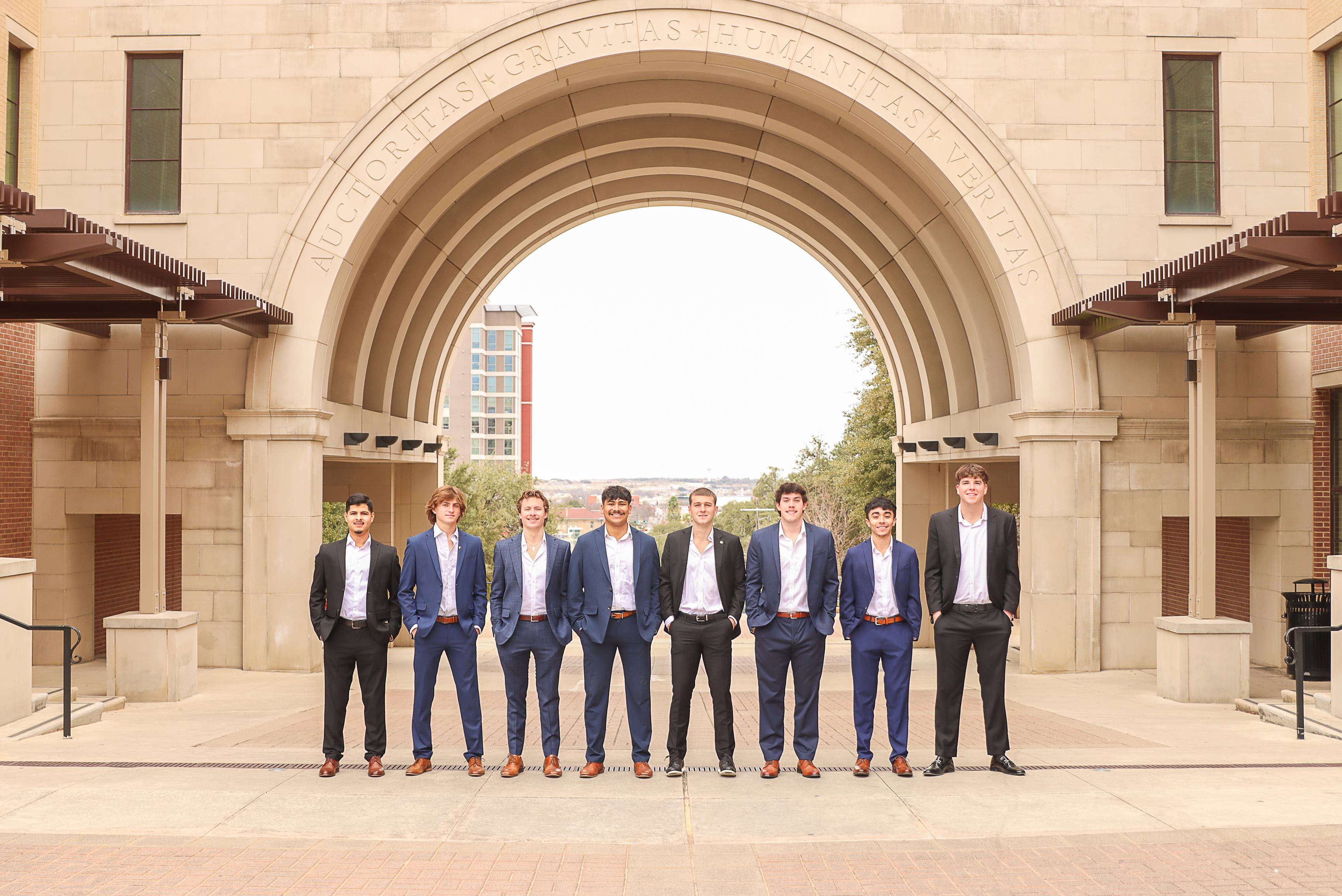 Men posing in front of TXST arch