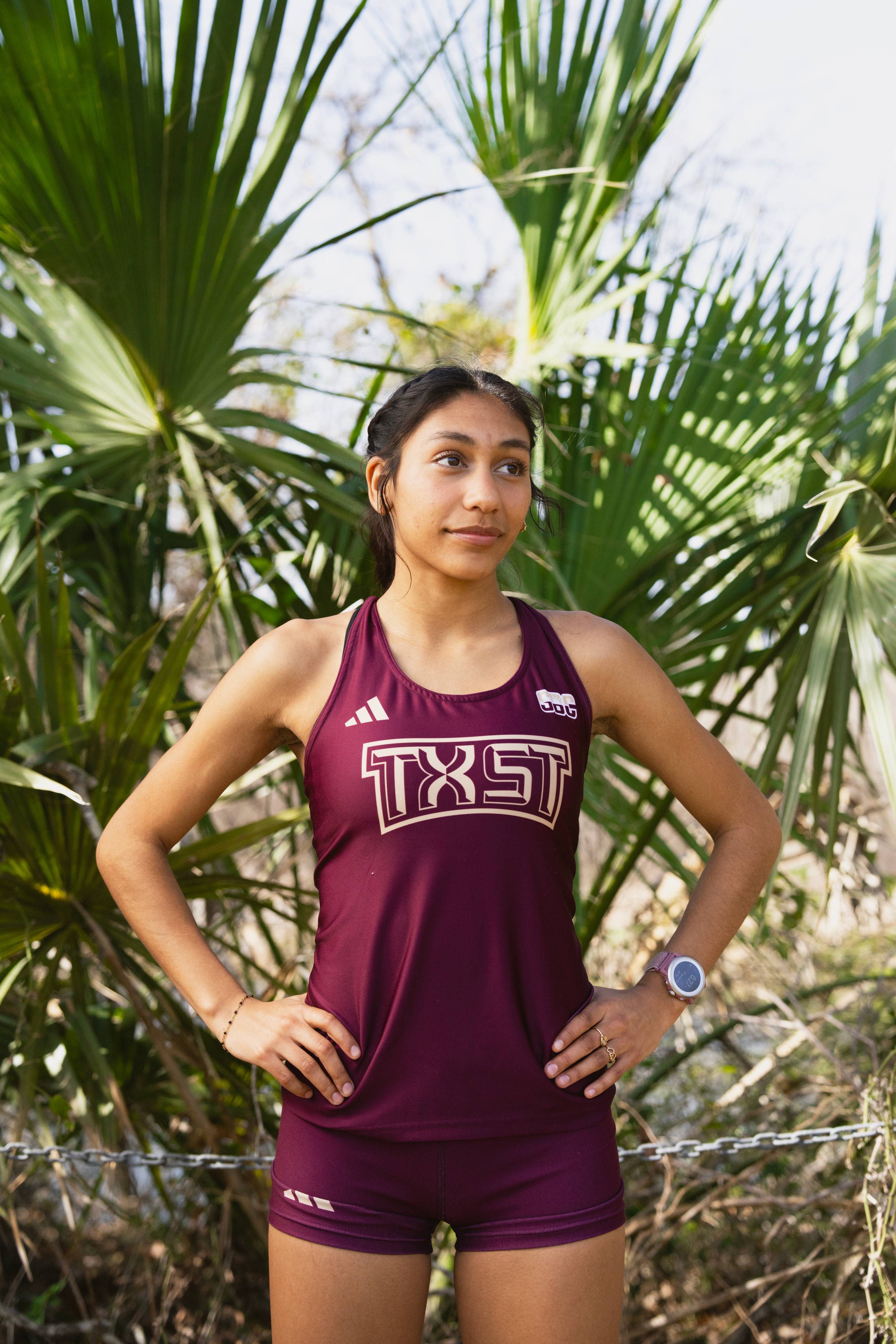 cross country athlete posing in front of a palm tree