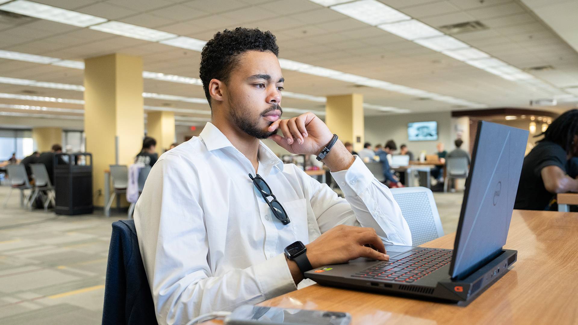 a student typing on a laptop in a library