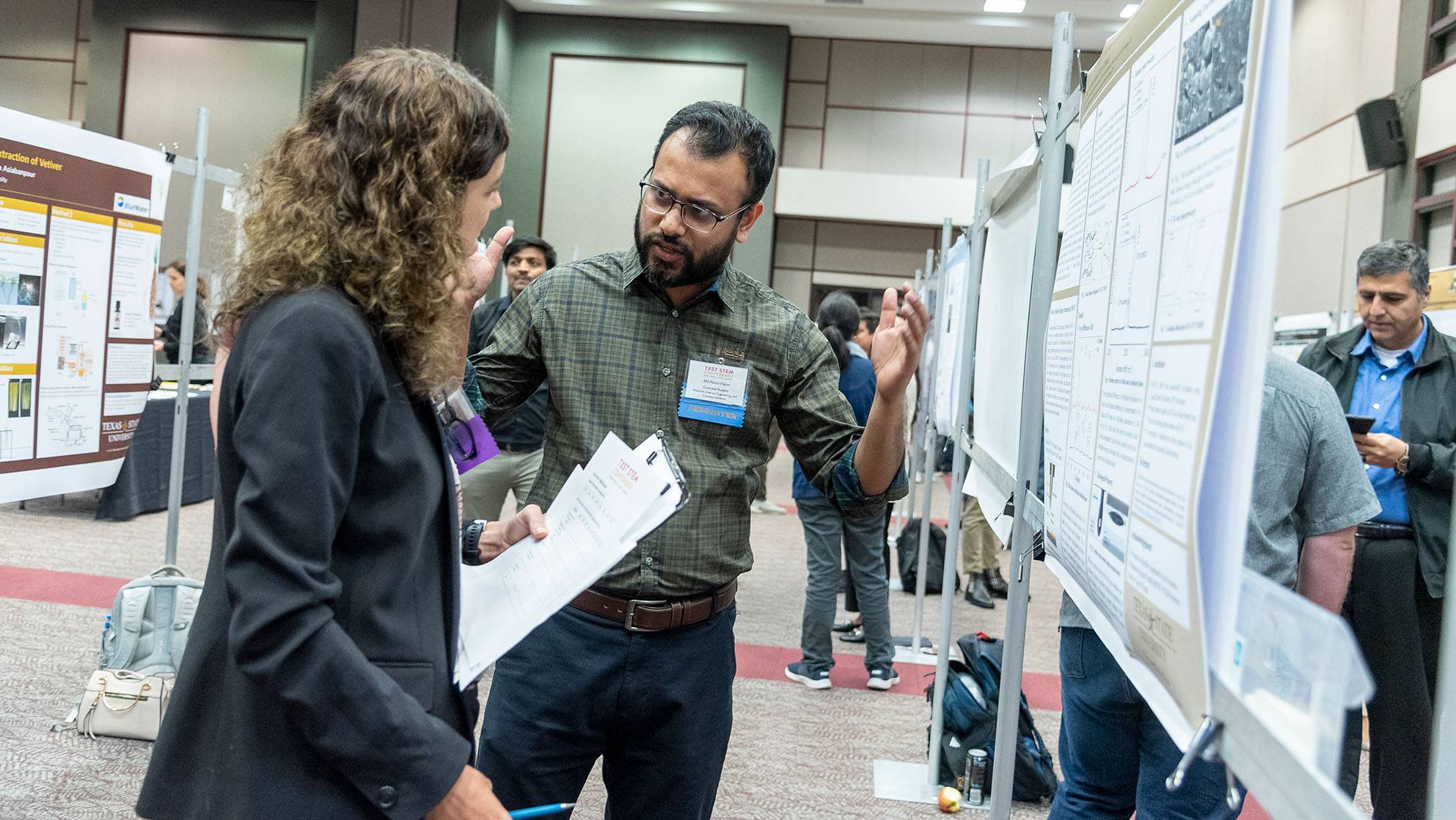 A researcher speaks to an attendee at a research conference.