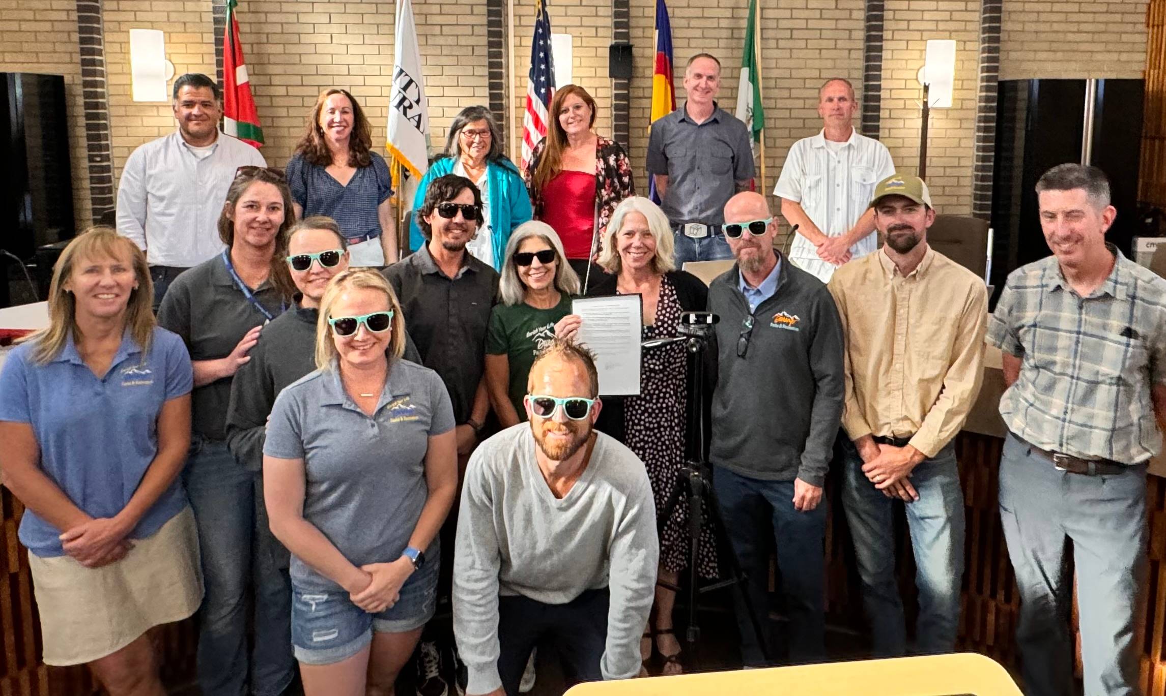 large group of people smile for a photo in a city hall meeting room 