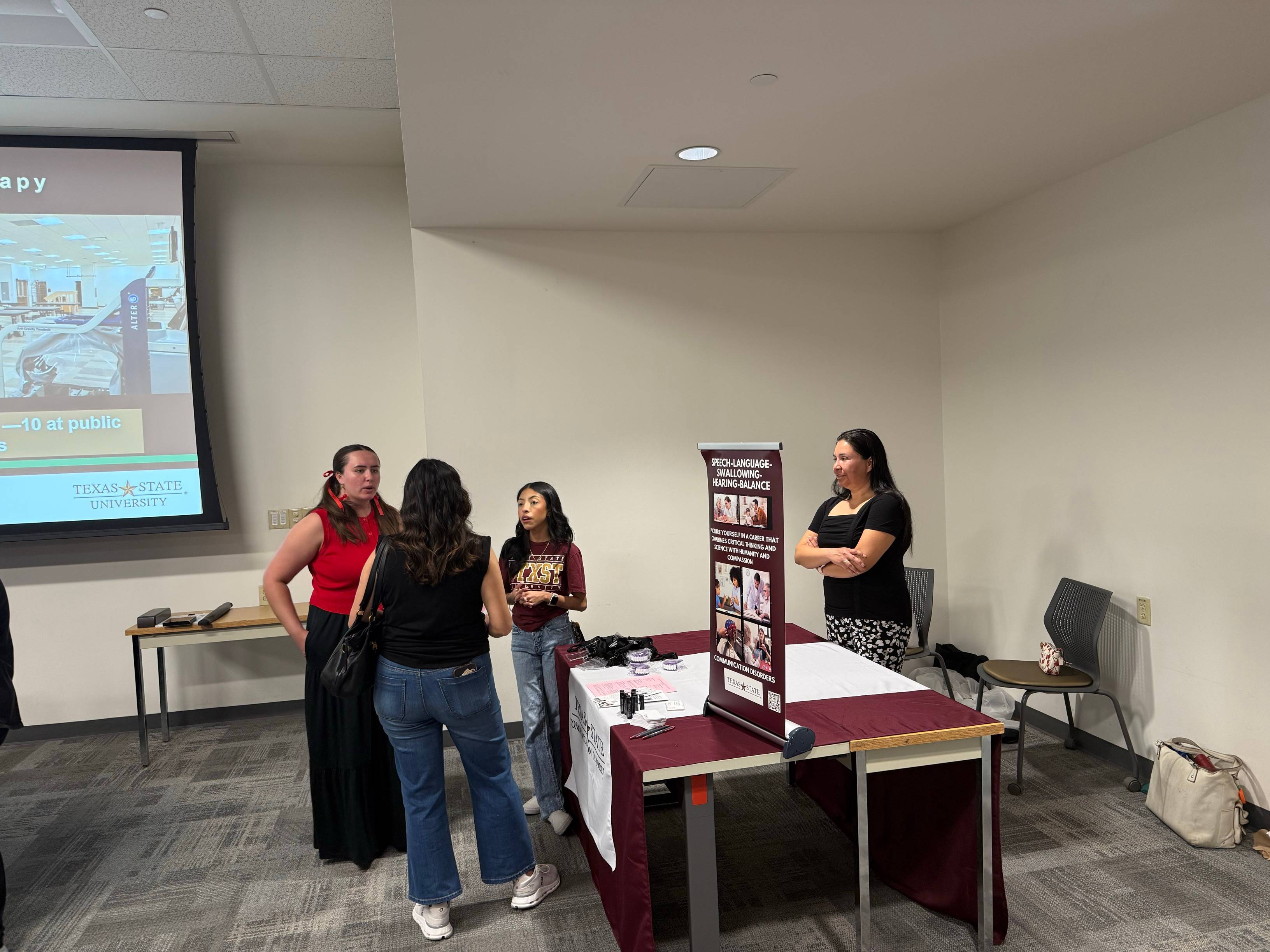 Dr. Resendiz and CDIS students standing next to their booth during the event.