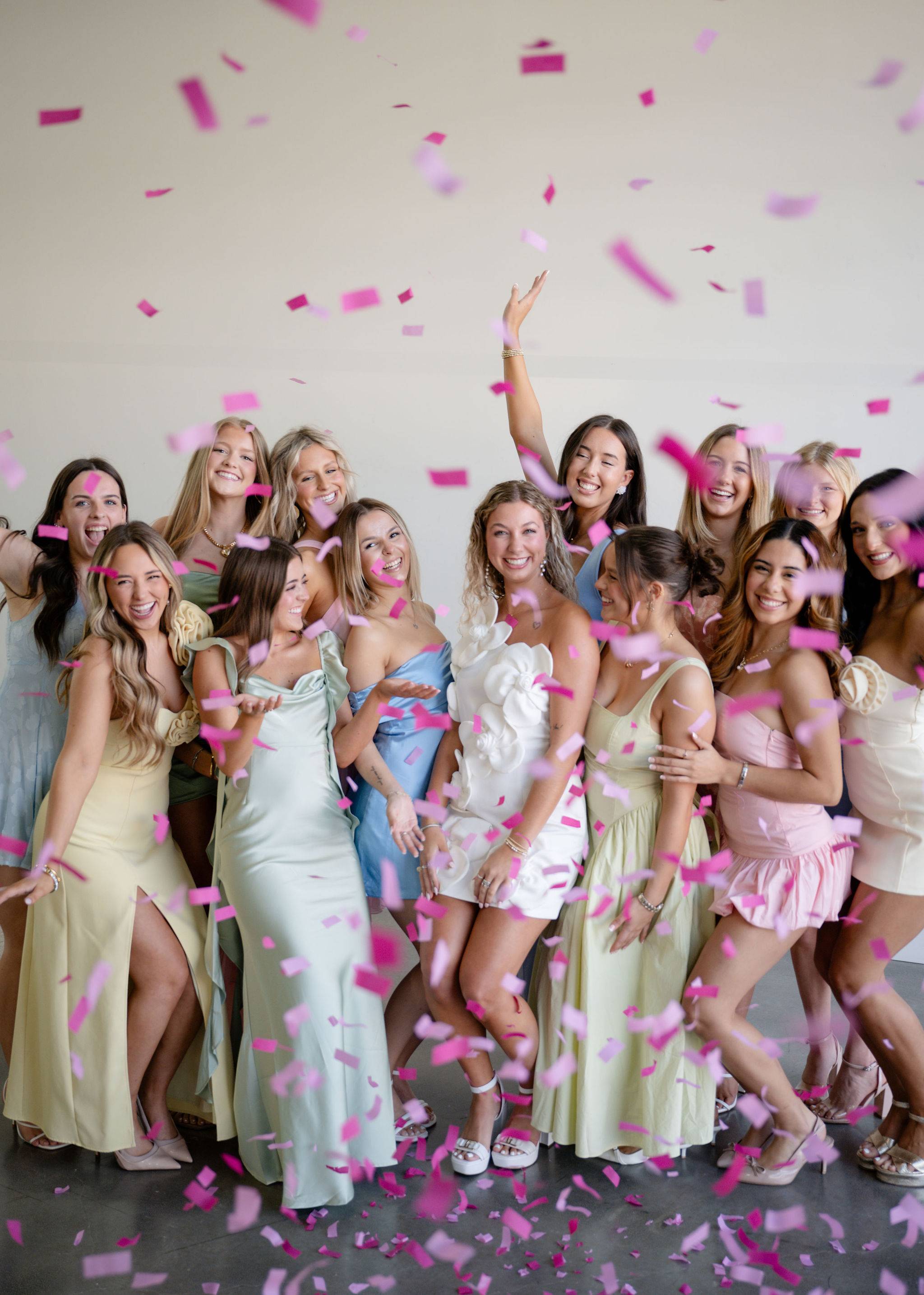 Two Zeta Tau Alpha women wearing matching white and black outfits holding up their organization's hand signs and posing with clouds in the background