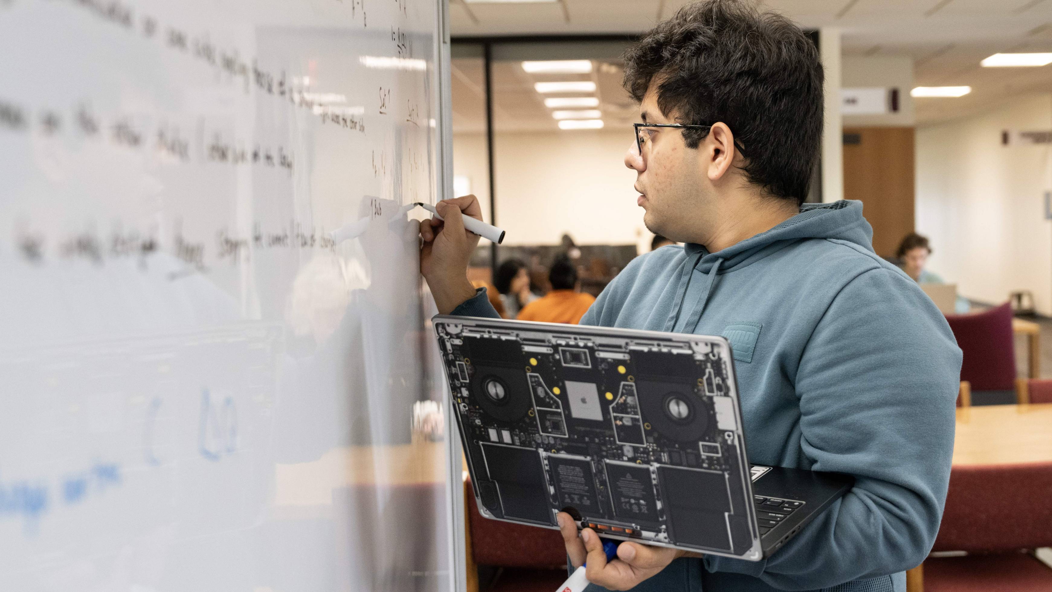 Student standing at whiteboard with laptop