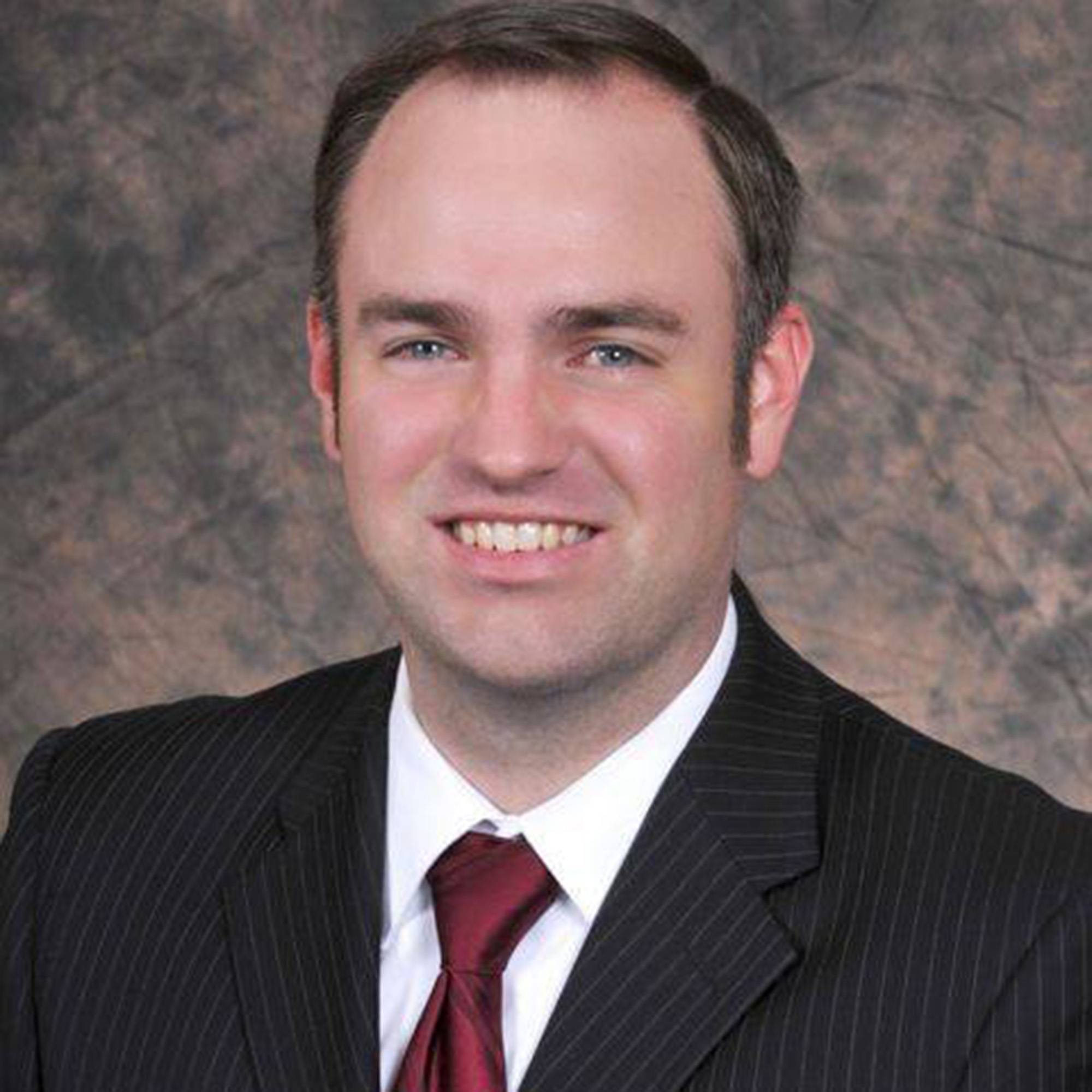 man dressed in professional attire smiling for headshot photo