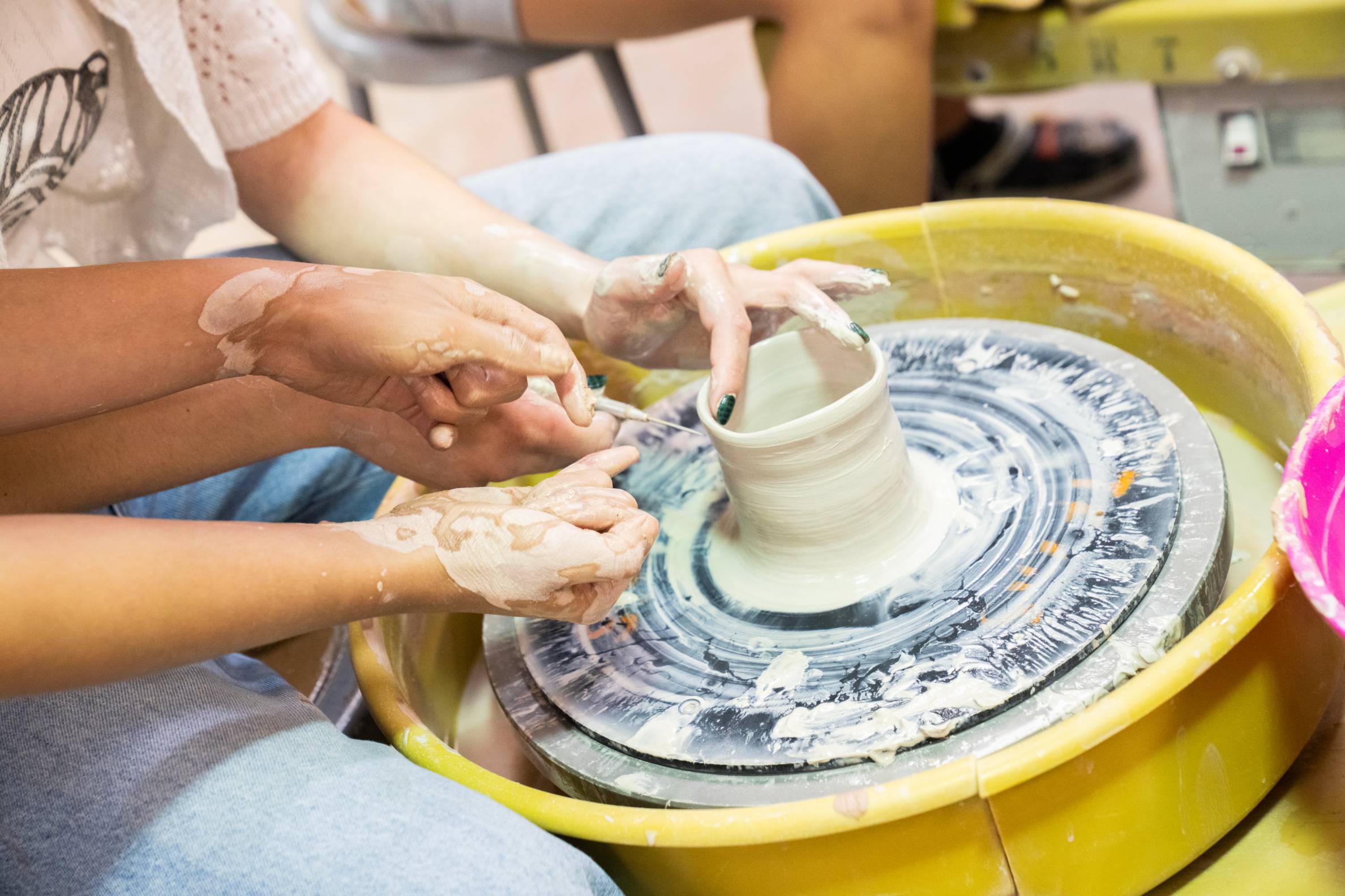a potter's wheel with students' hands creating a design
