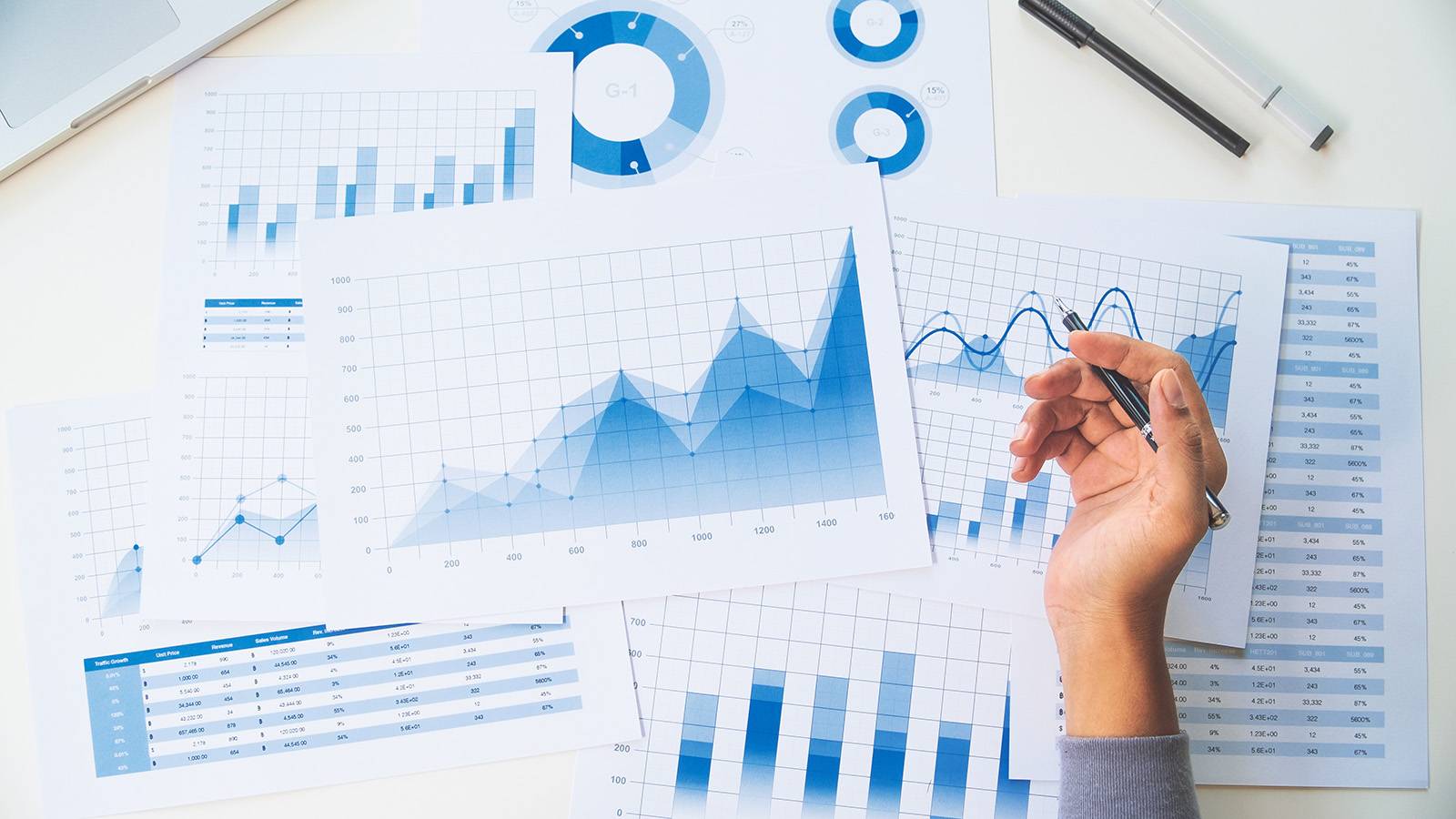 person working on numerous documents with various types of graphs