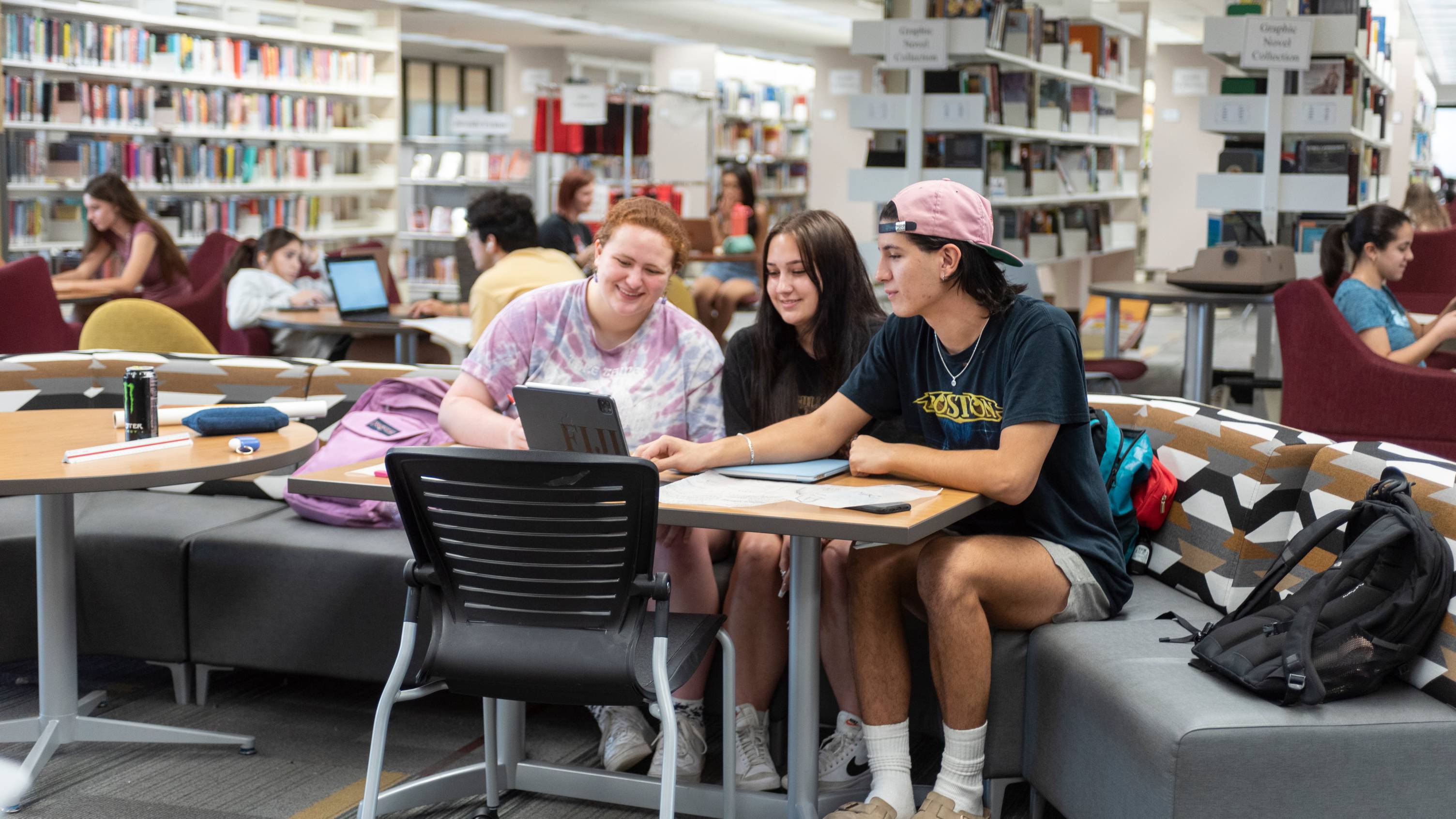 students sitting in a library looking at a laptop