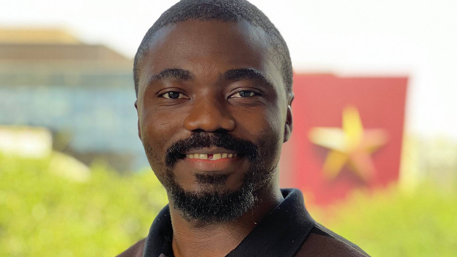 Augustine Tarkom smiling in headshot photo with blurred scenic background