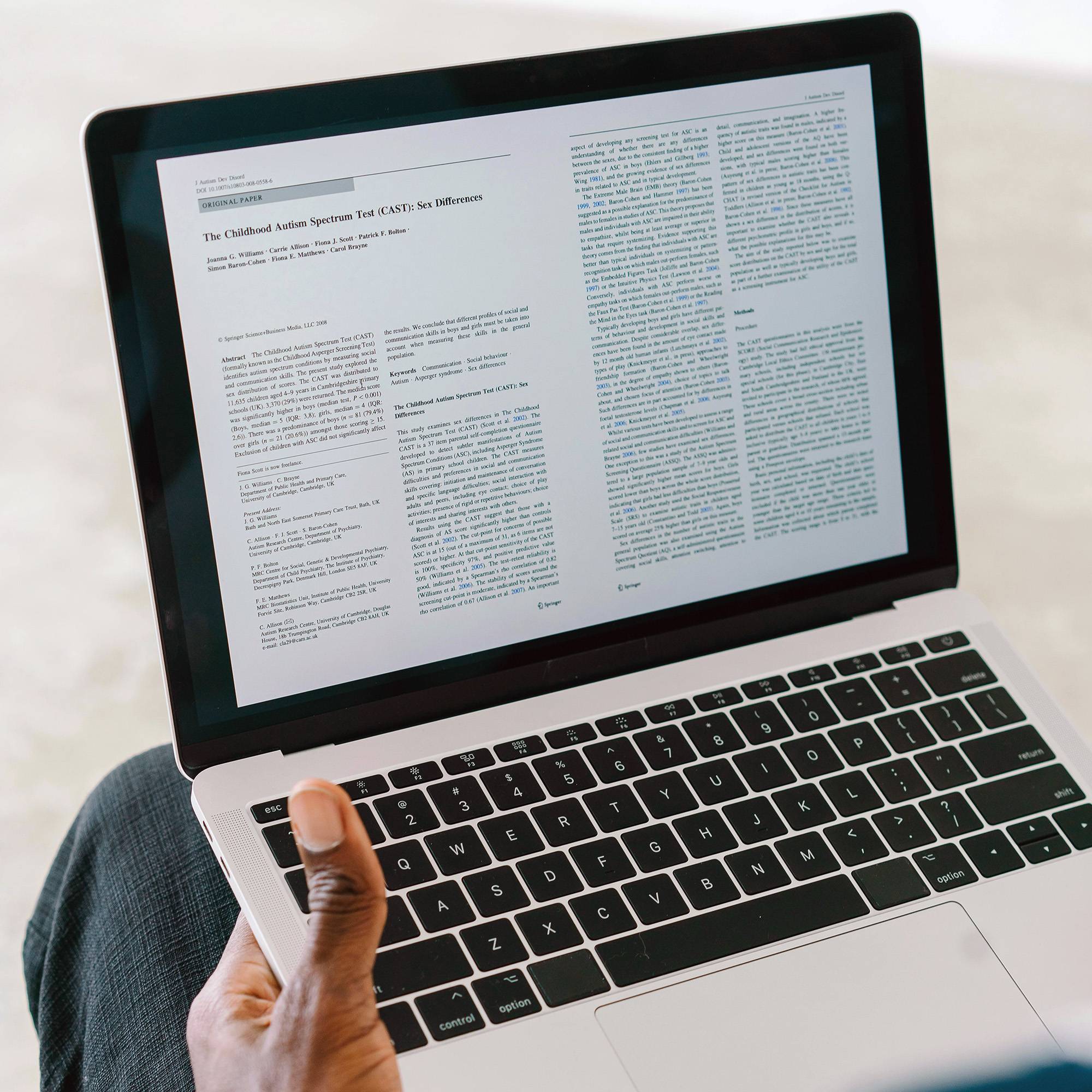 person holding laptop while reading academic article
