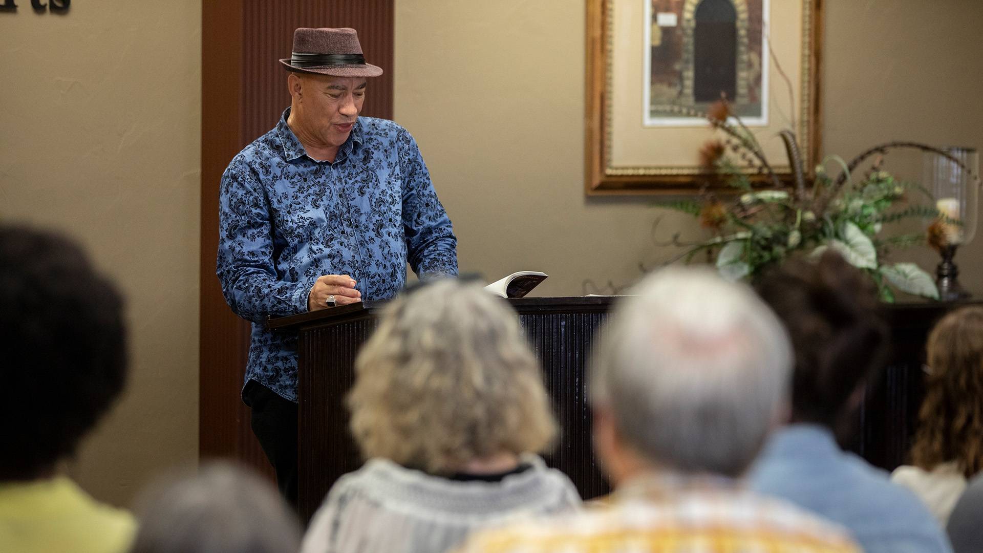 cyrus cassells reading at a podium 
