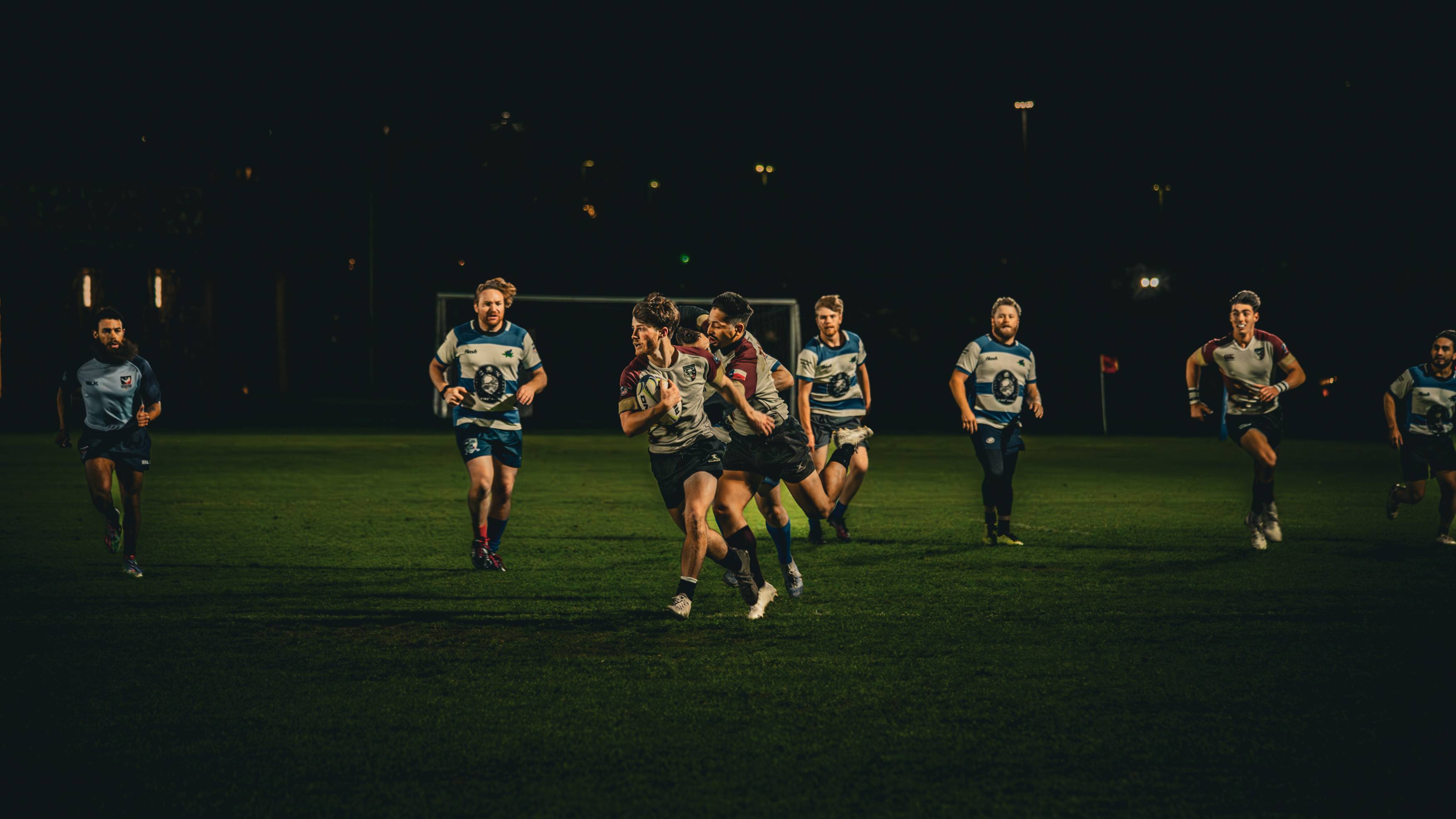 Men's Rugby player running with rugby ball down the field 