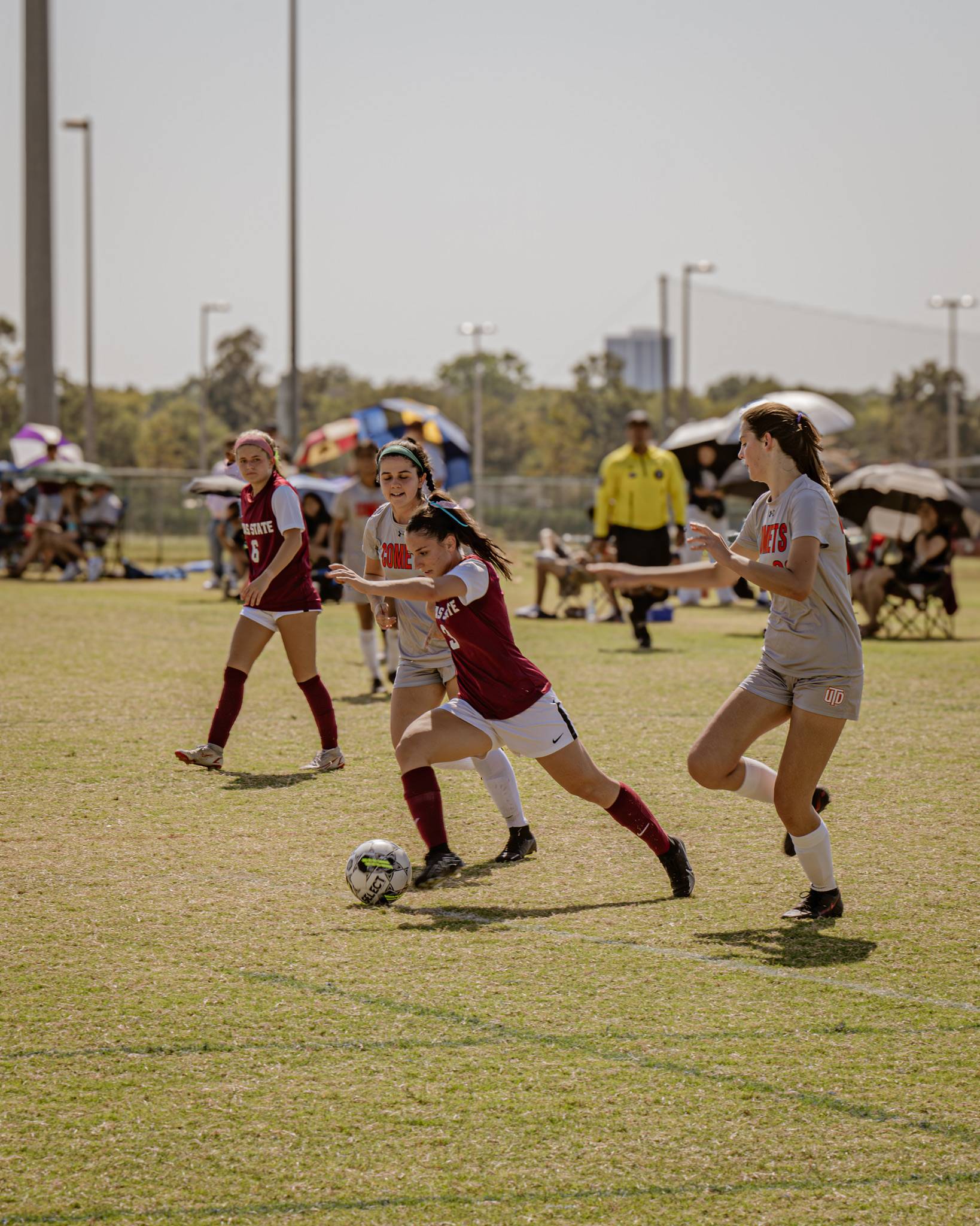 women's soccer striding for a soccer ball with defenders around her