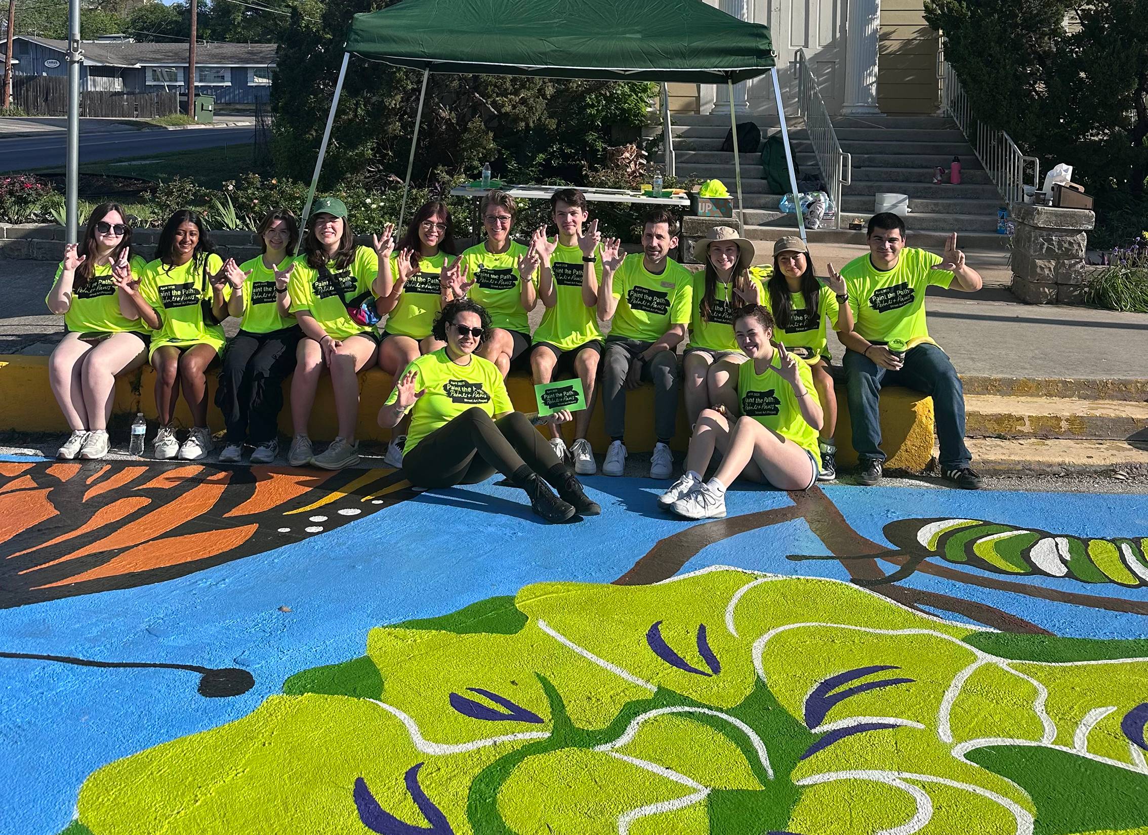multiple people wearing safety vests are painting on a concrete sidewalk
