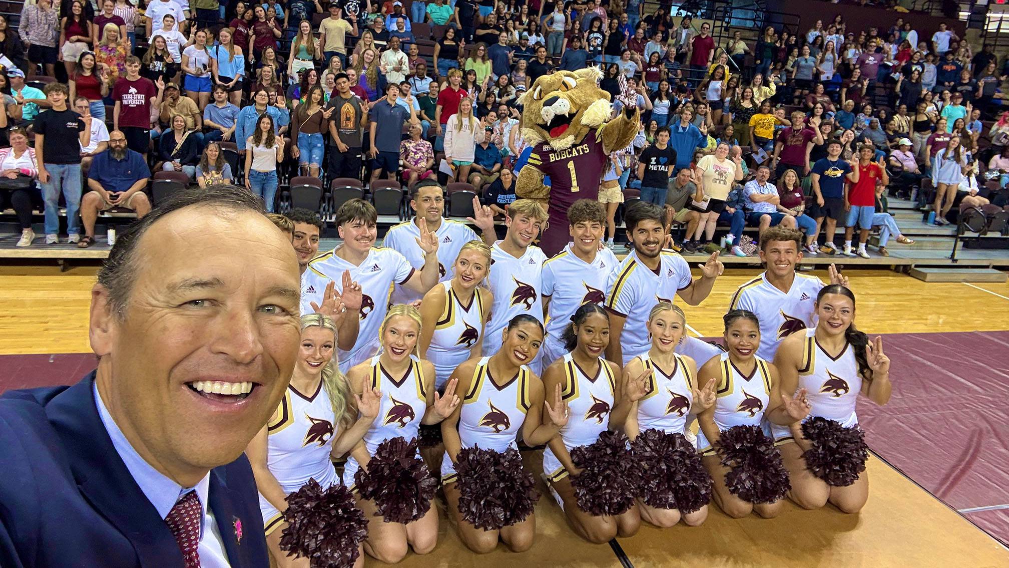 President Kelly Damphousse (left) takes a selfie with a crowd of cheerleaders and incoming freshmen at the UEC.