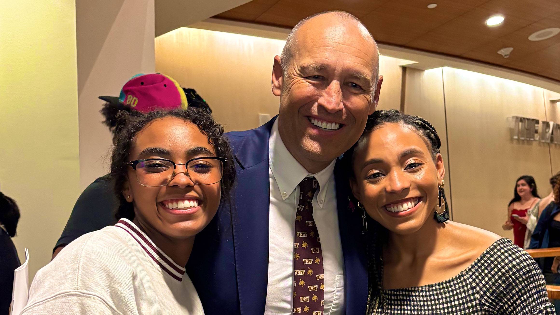 President Kelly Damphouse (middle) poses for a photo two students in the Performing Arts Center.