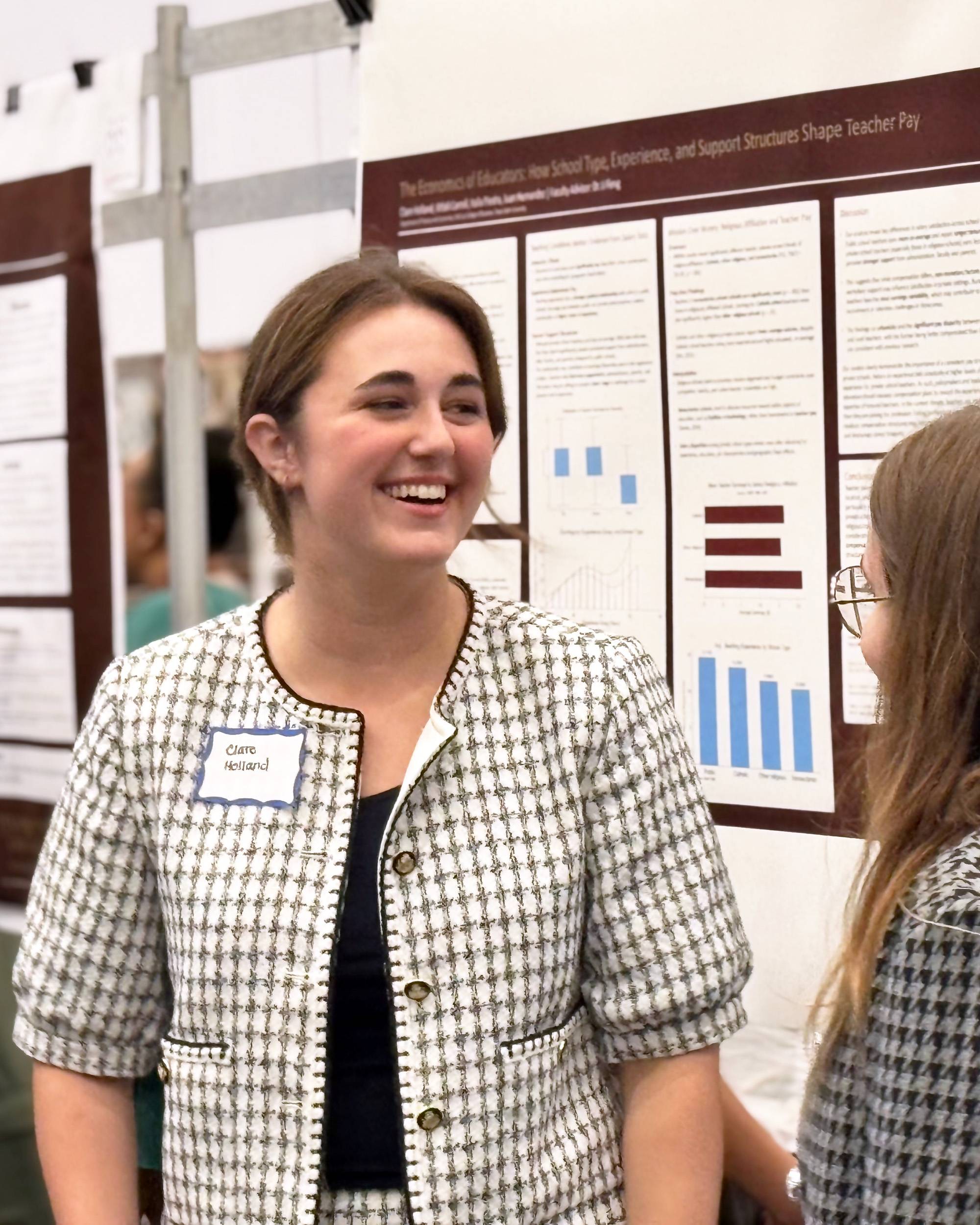 Young woman in business attire smiling while presenting a poster