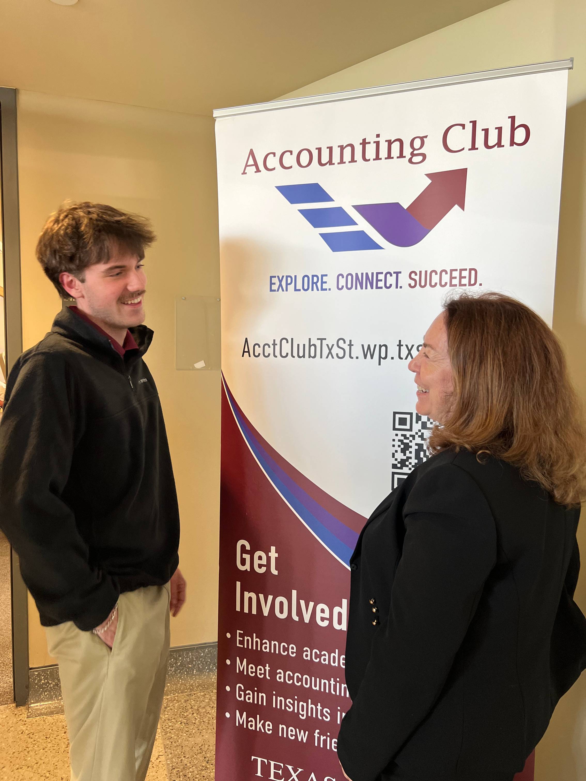 two people talking in front of a poster