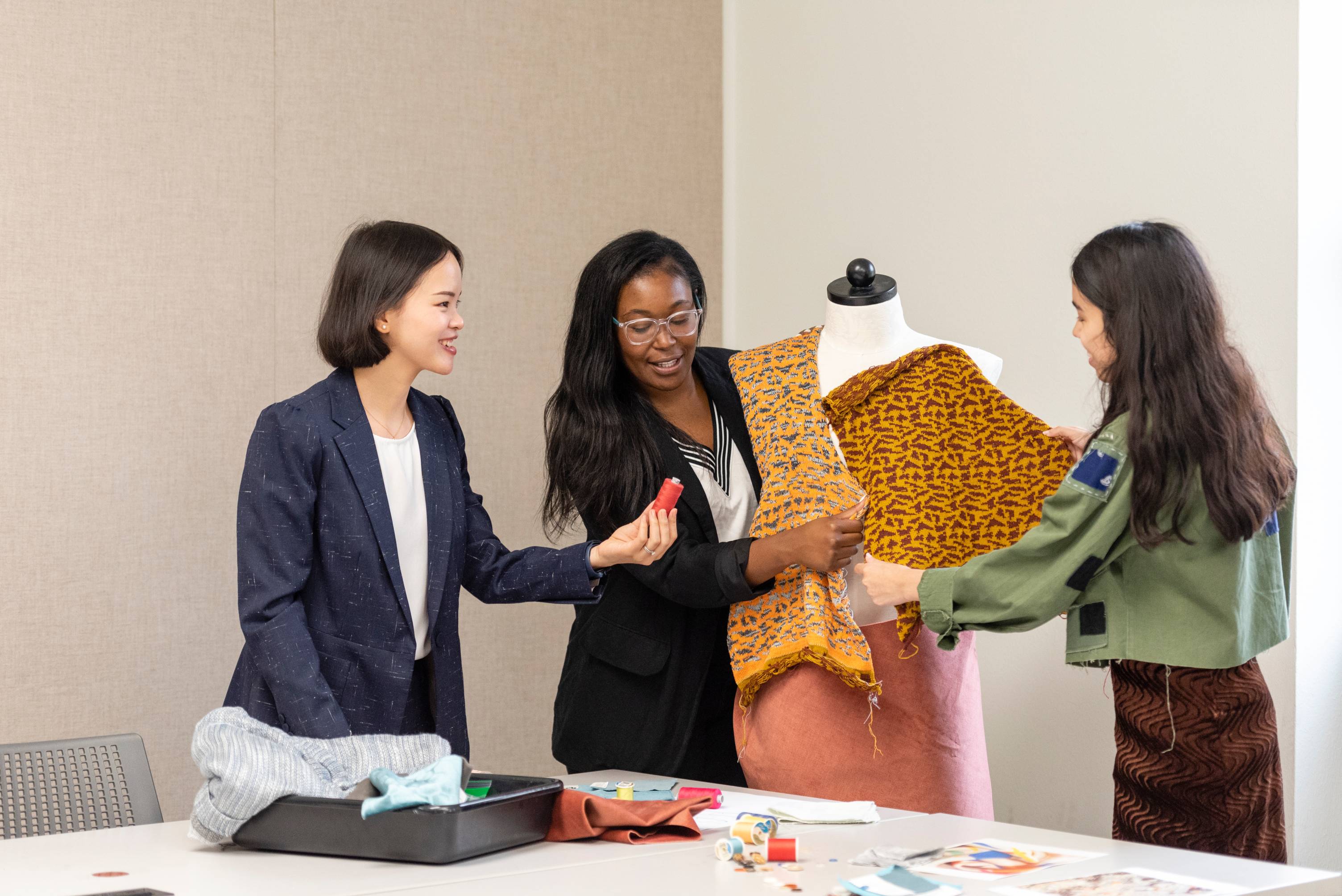 faculty and students with mannequin examining textiles