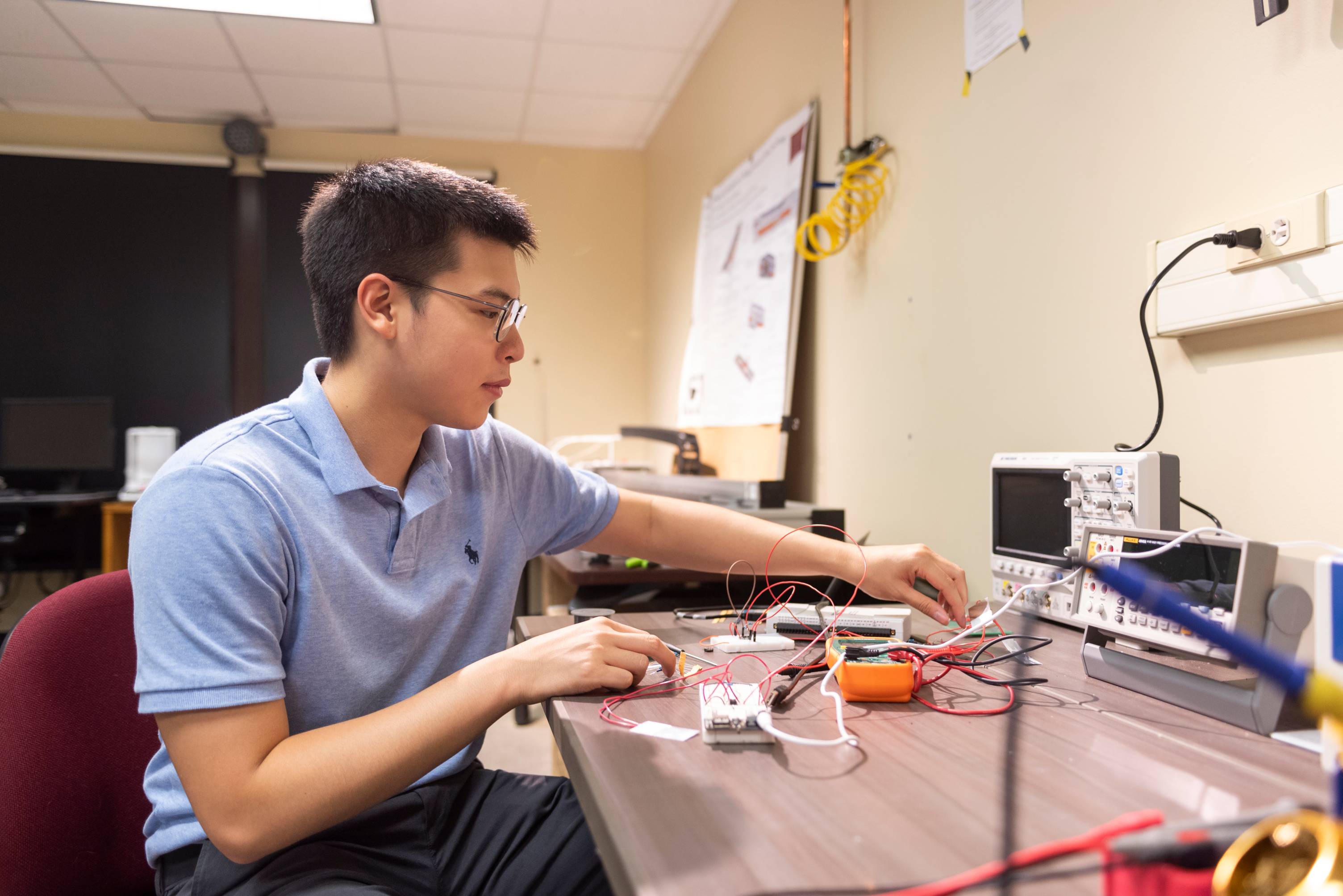 student at desk with electronics