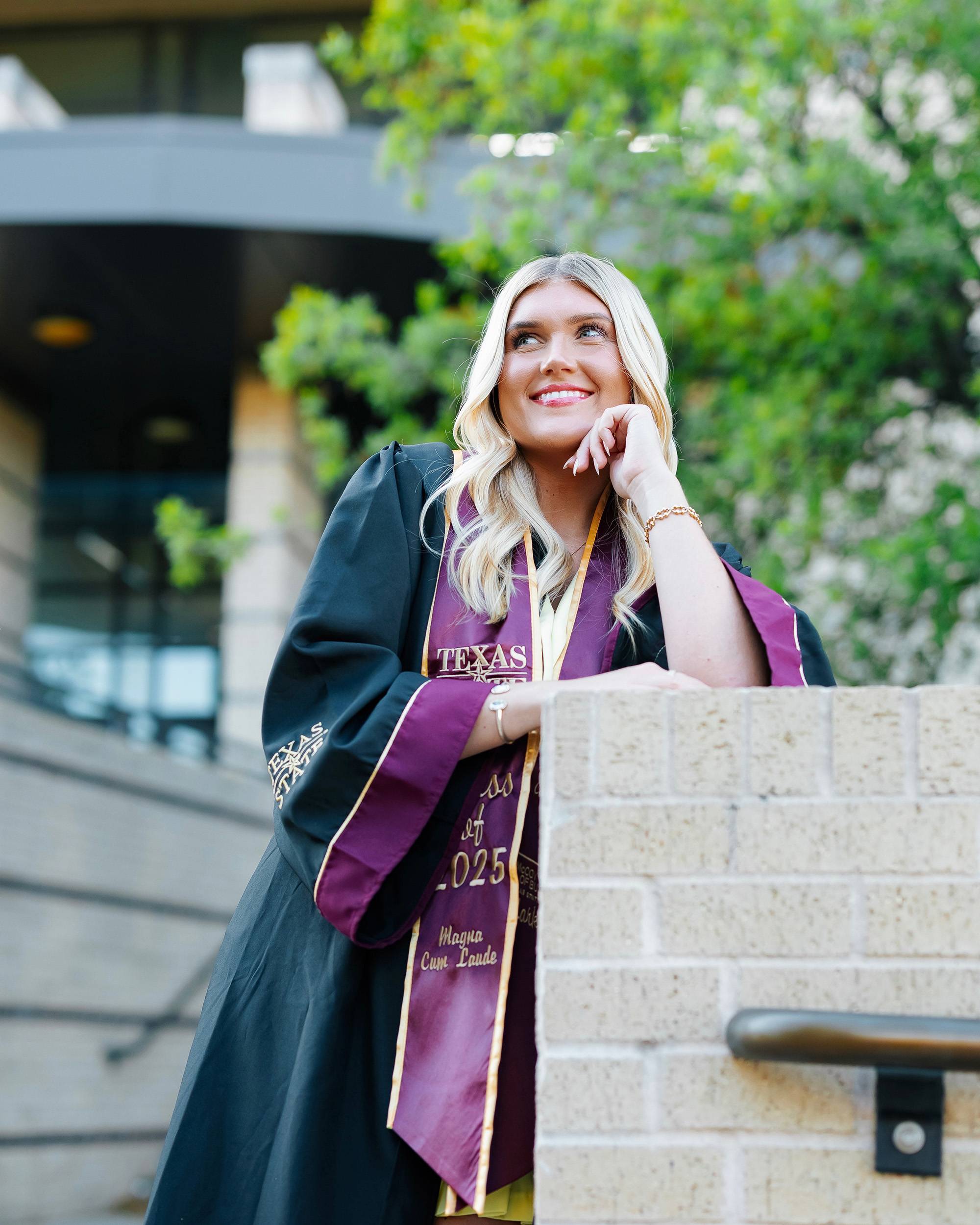 Young woman in graduation regalia posing outside McCoy Hall