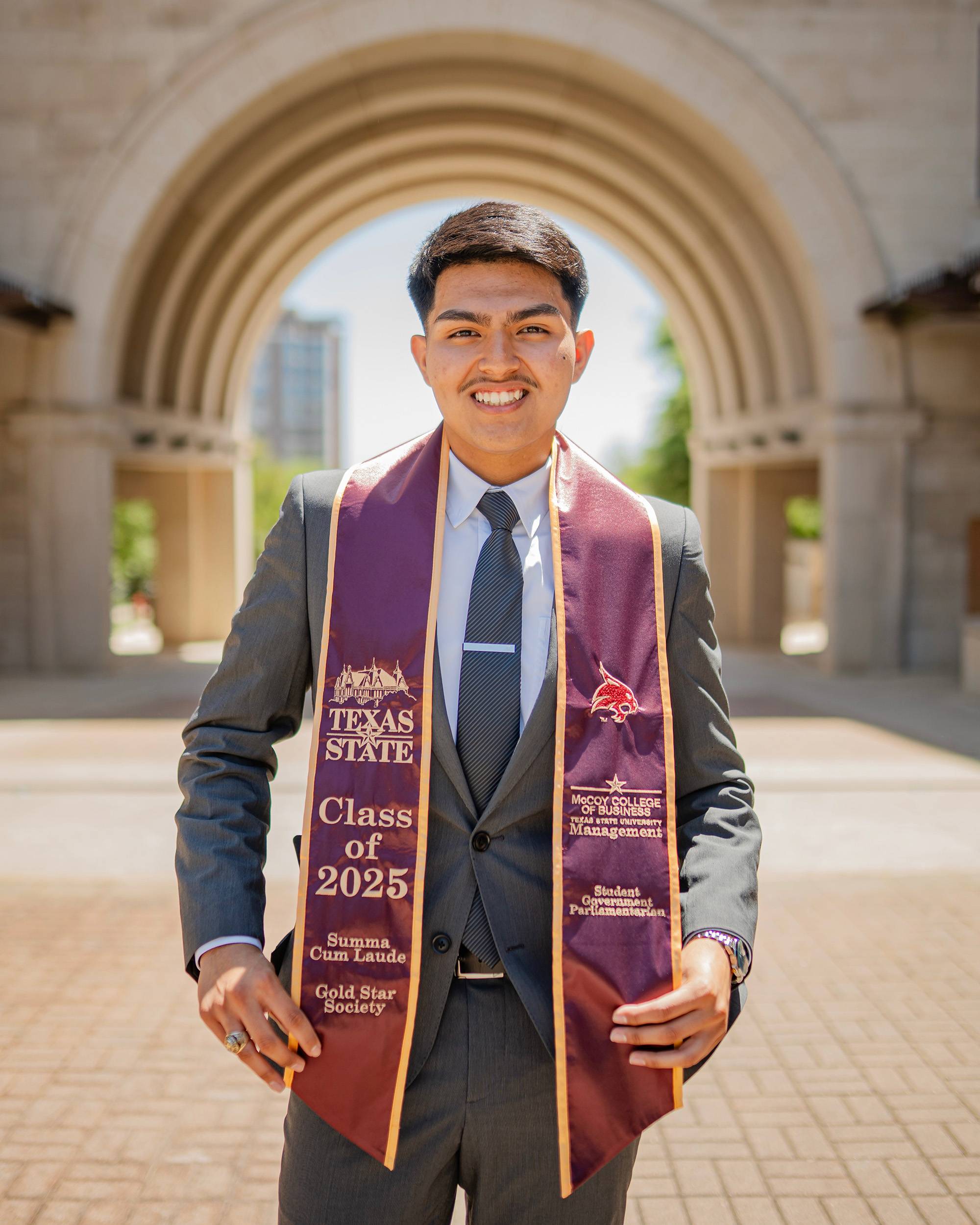 Young man outdoors in business suit with graduation stoles