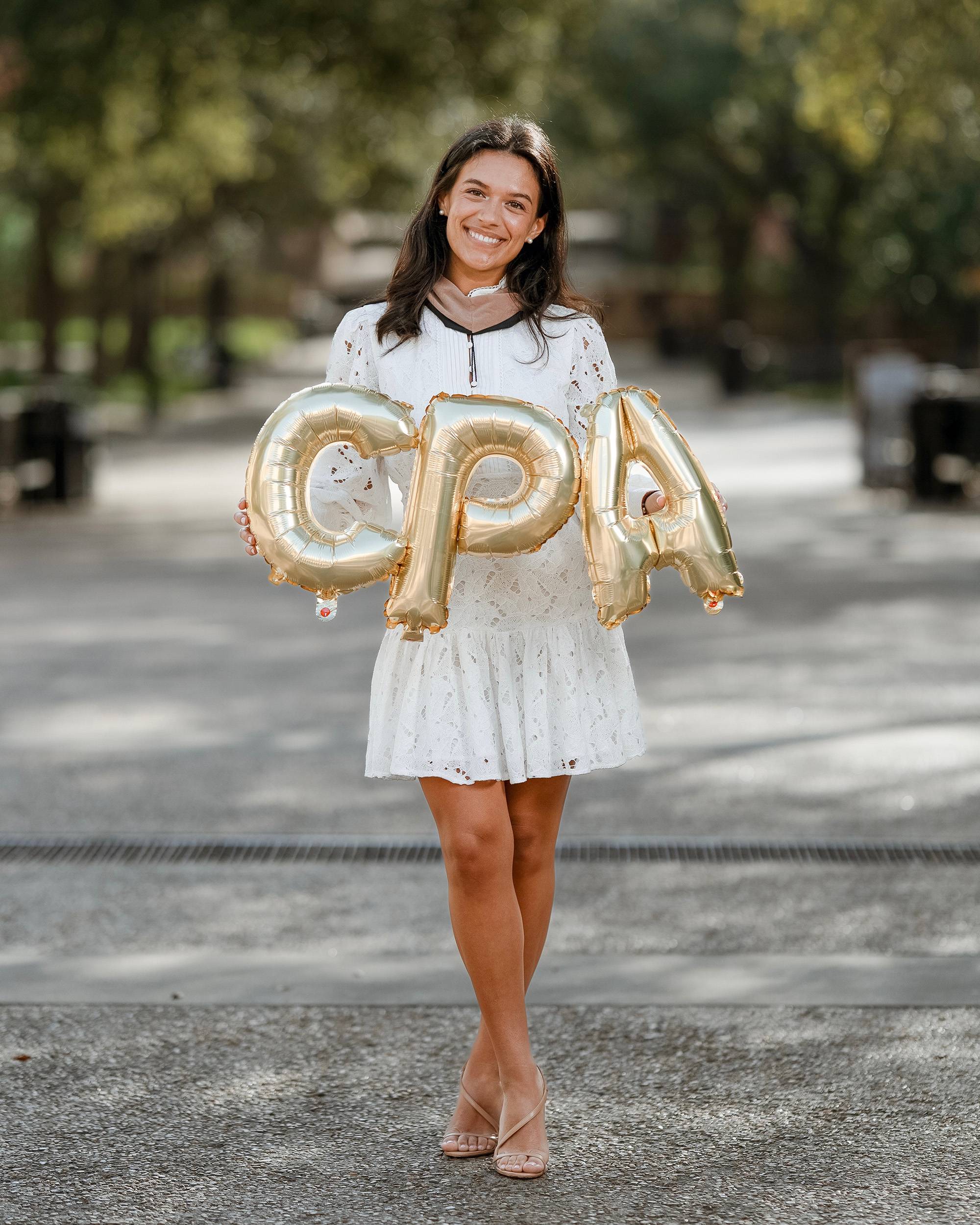 Young woman outdoors holding balloons that spell CPA.