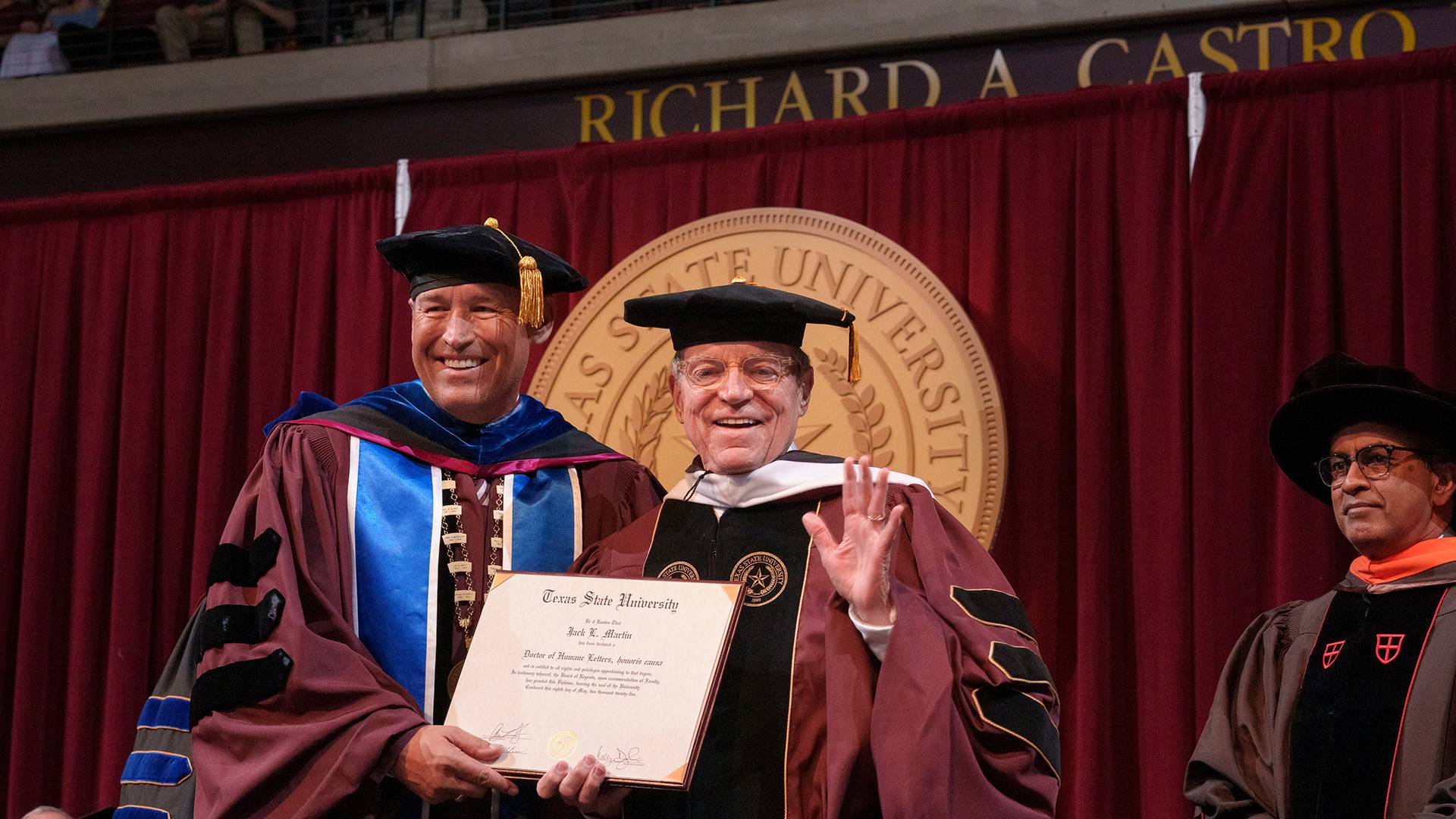 two people holding a diploma on a stage
