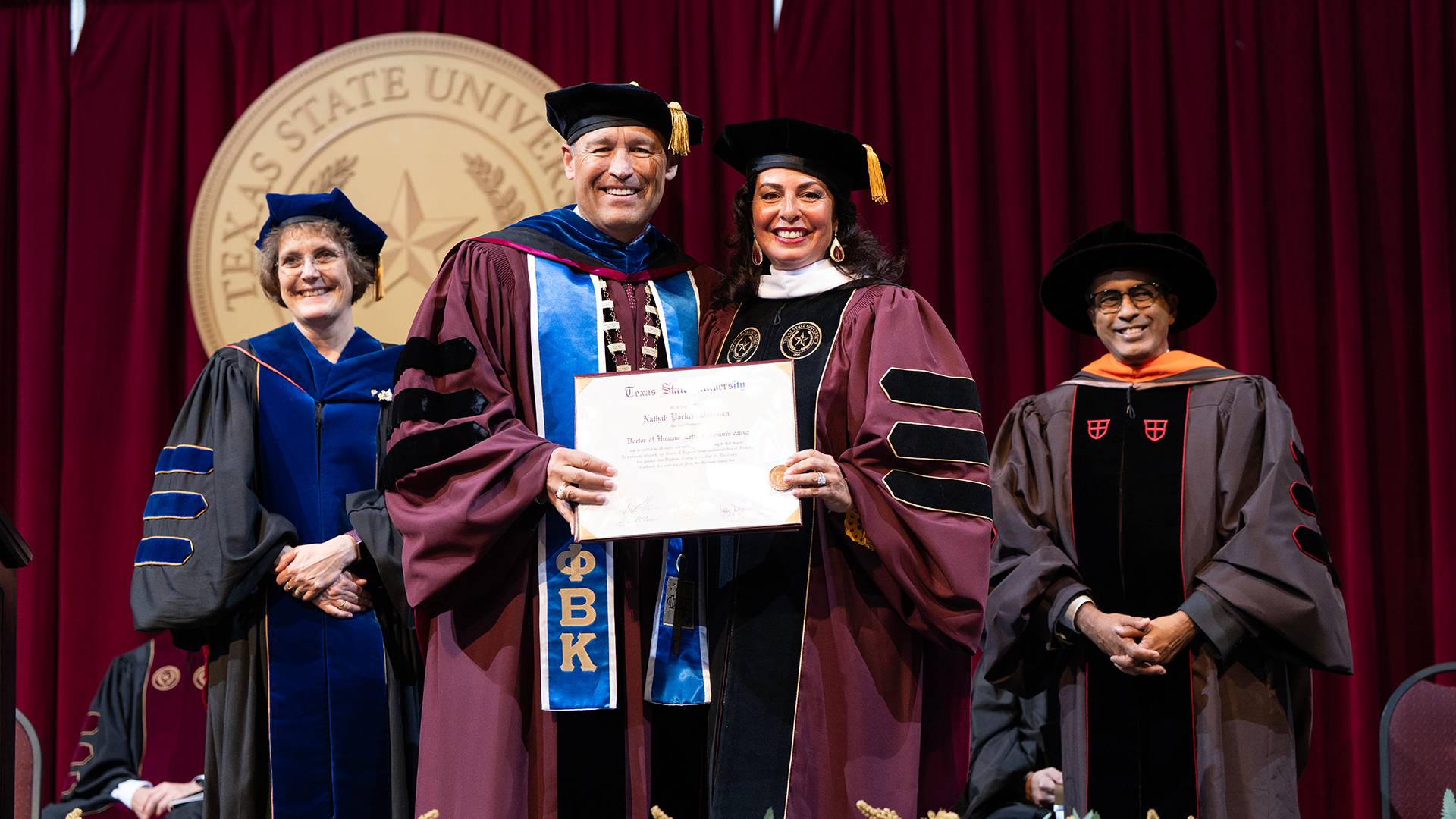 two people holding a diploma on a stage