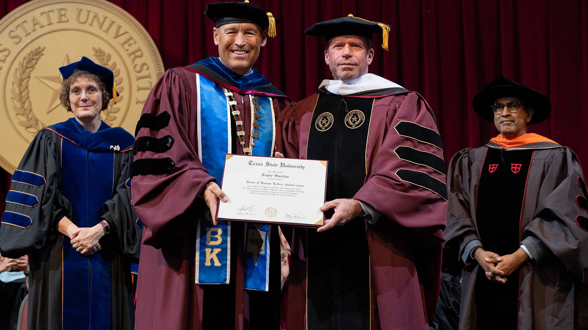 two people holding a diploma on stage