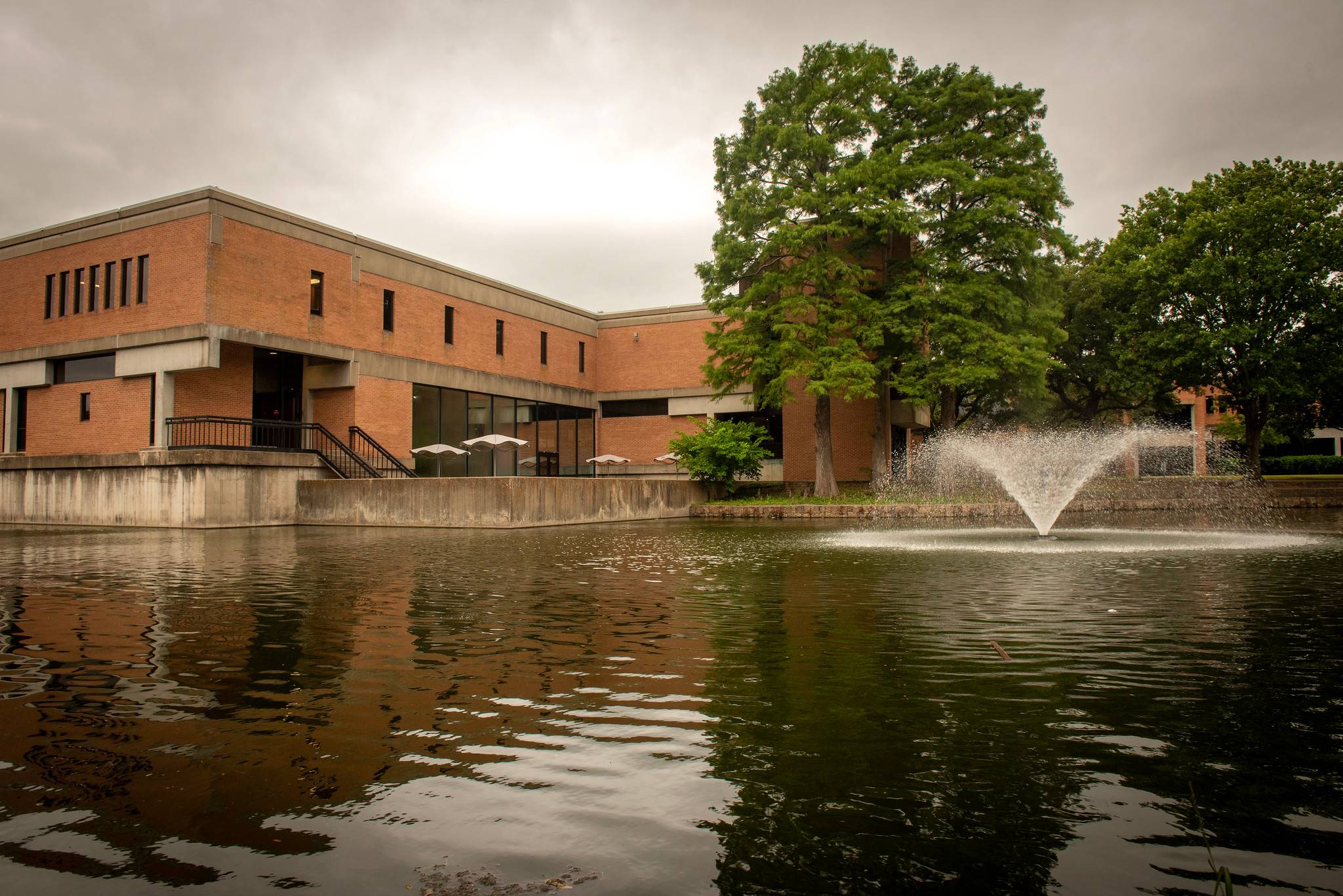 exterior of brick building behind body of water with fountain