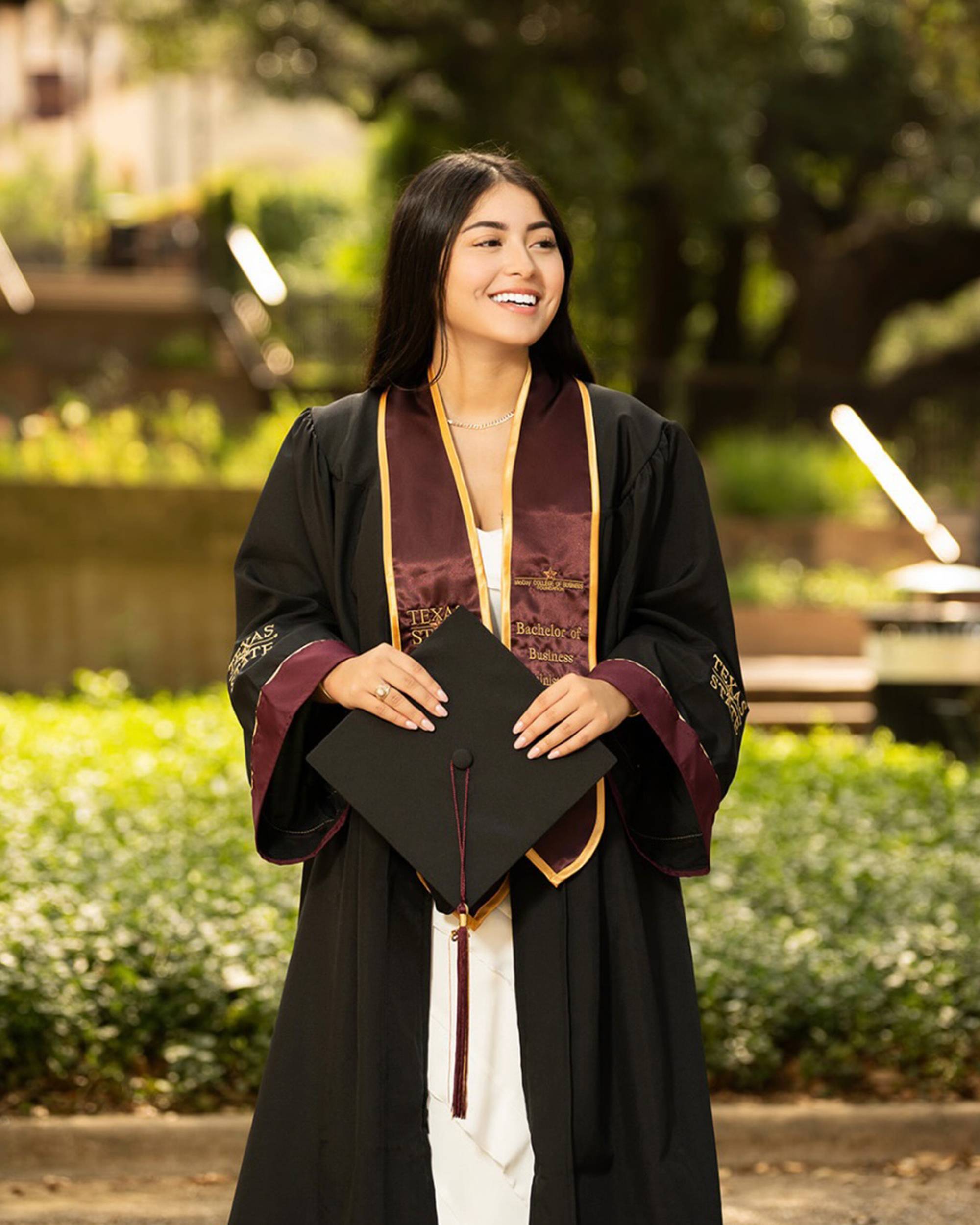 Kate Ramirez outdoors wearing graduation regalia
