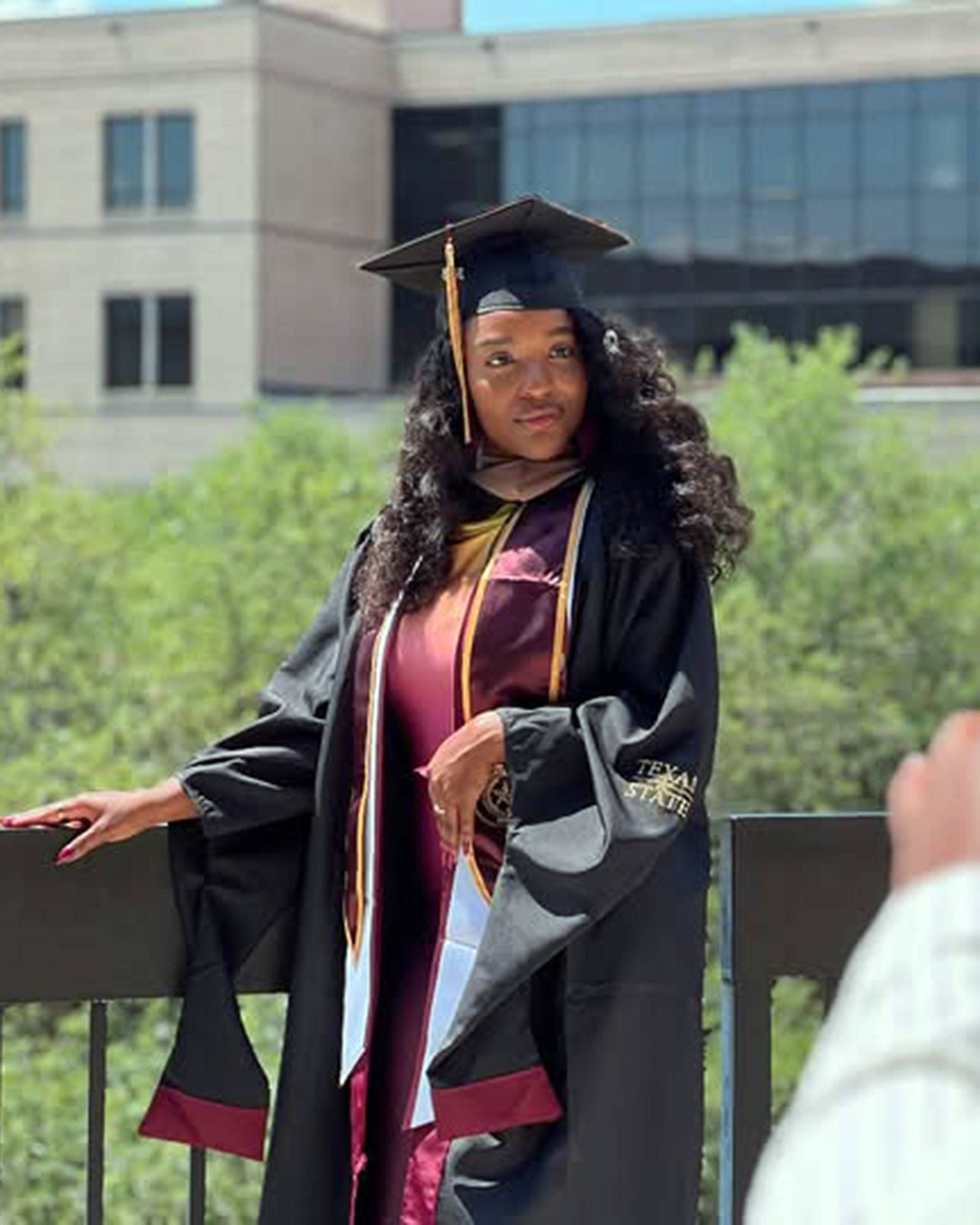 Young woman outdoors posing in graduation regalia