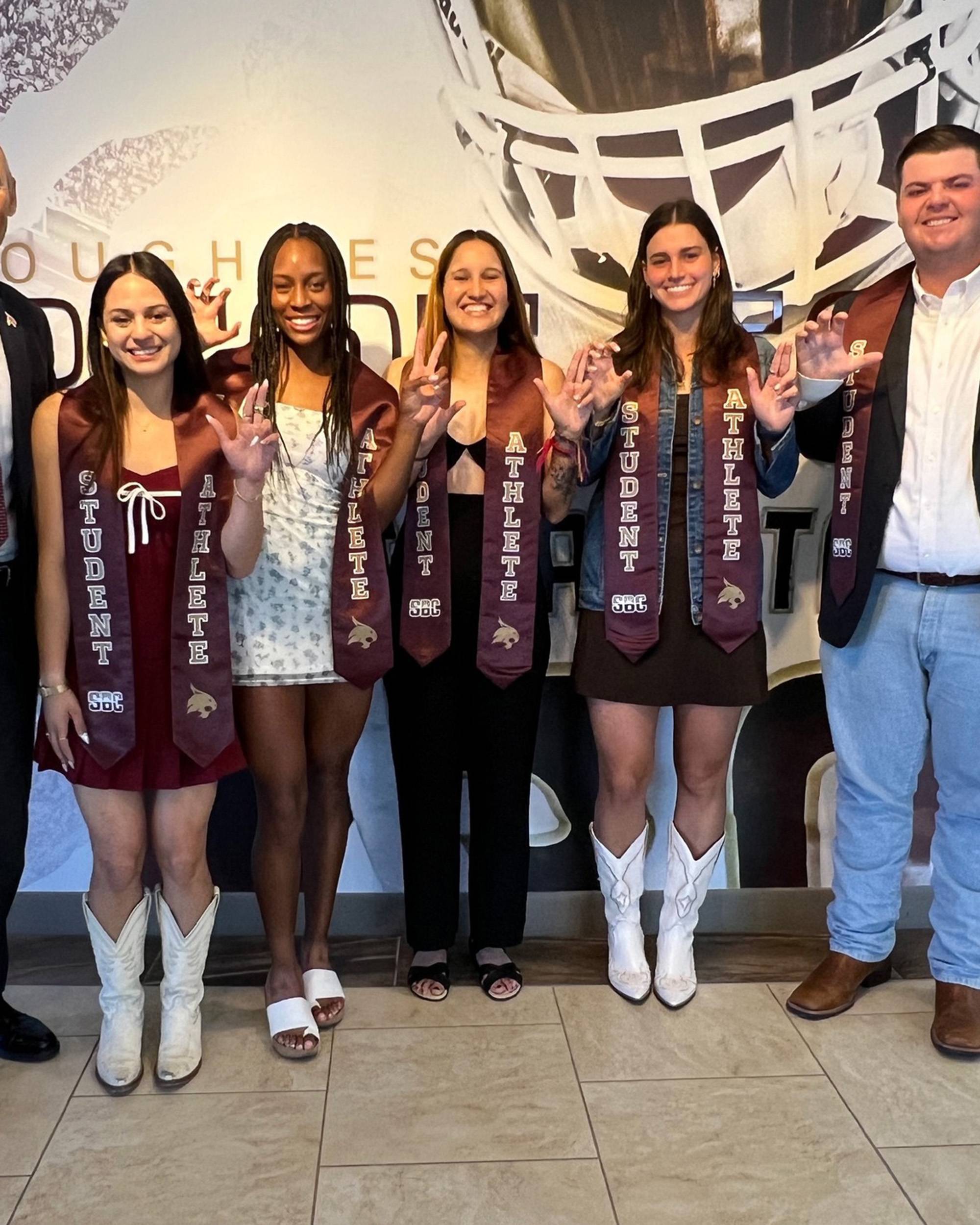 Five college students posing in graduation stoles that read, "Student Athlete"