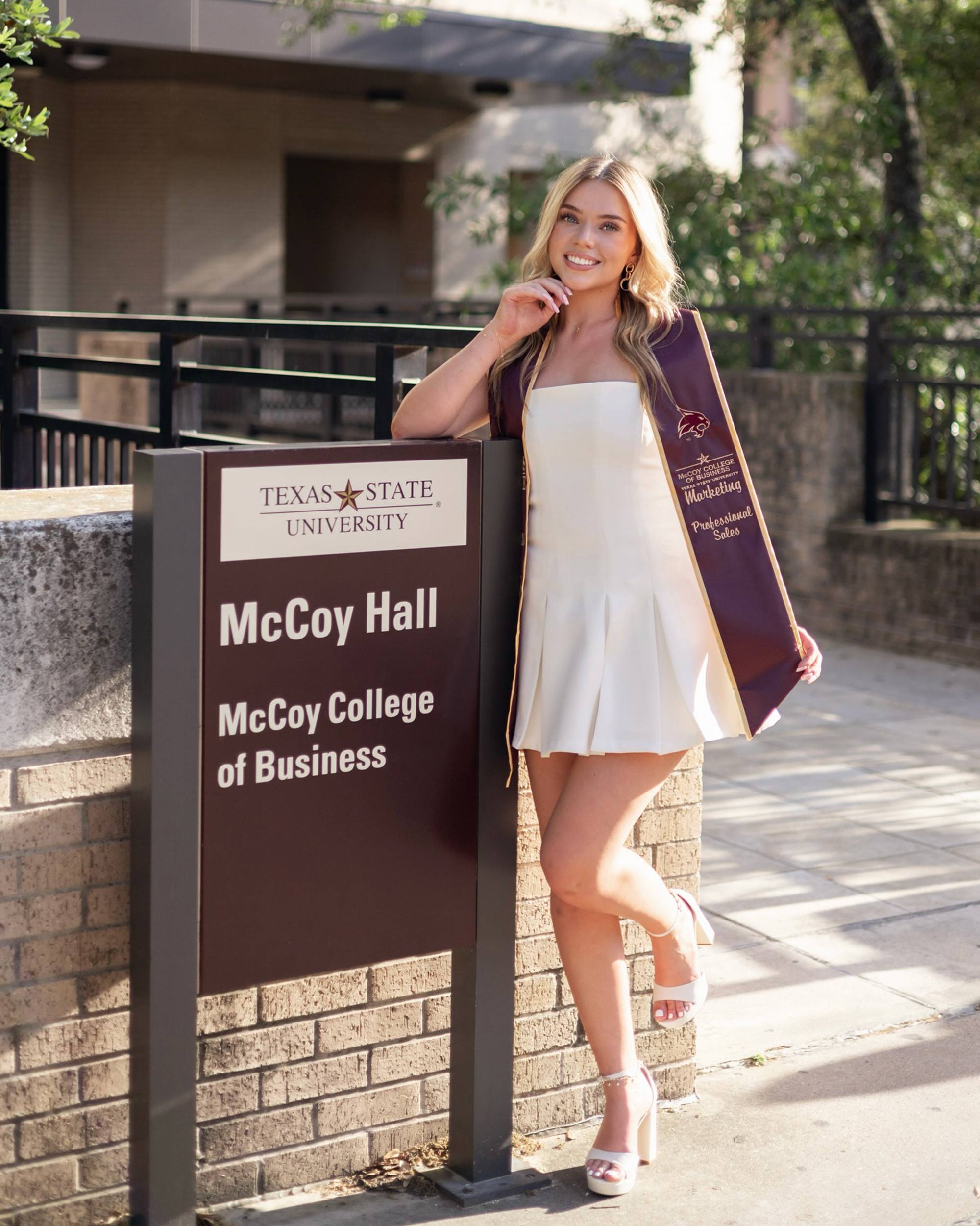 Savannah Lancaster posing outdoors in white dress with graduation stole
