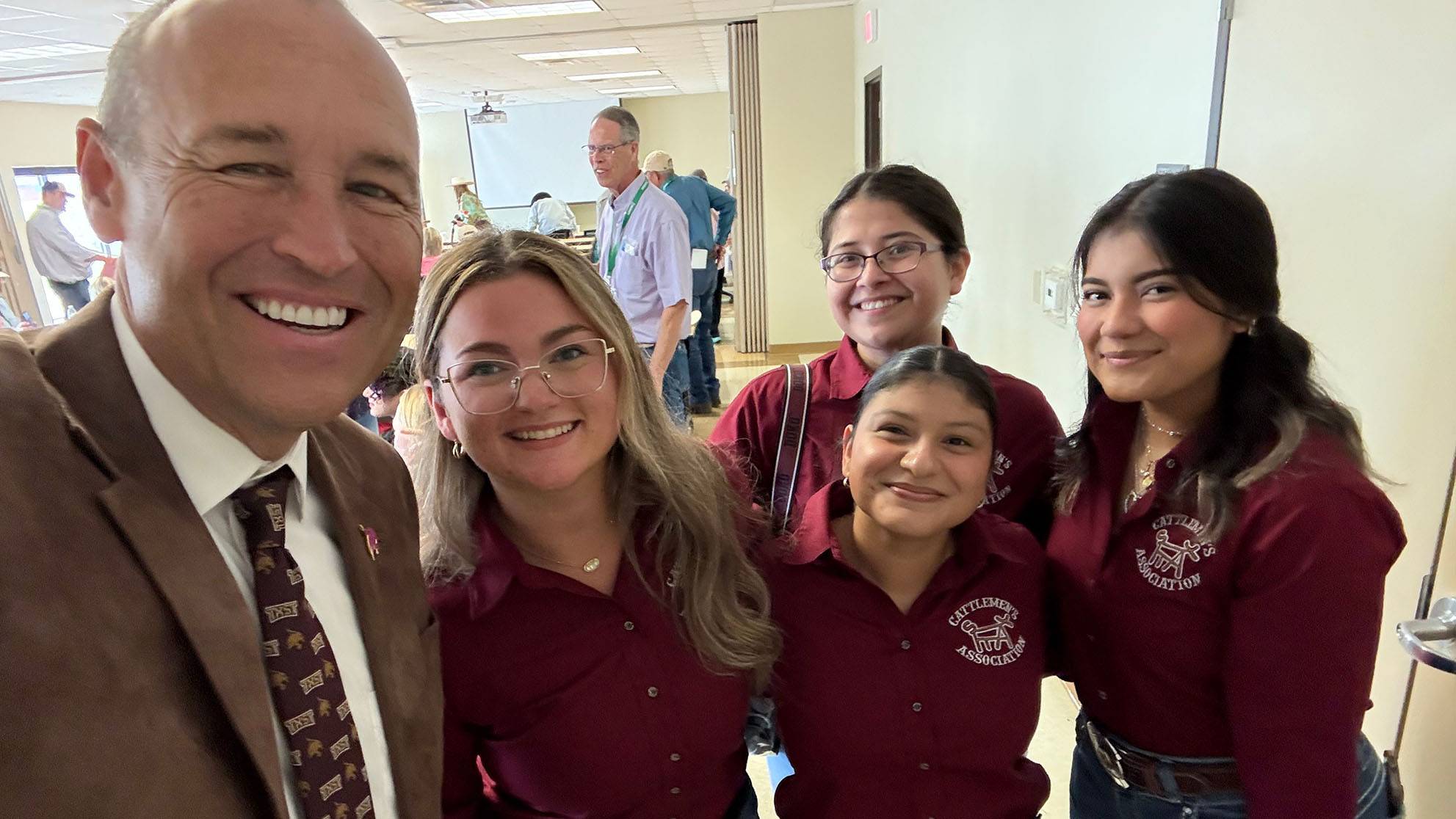 President Kelly Damphousse (left) poses for a photo with students at Freeman Ranch.