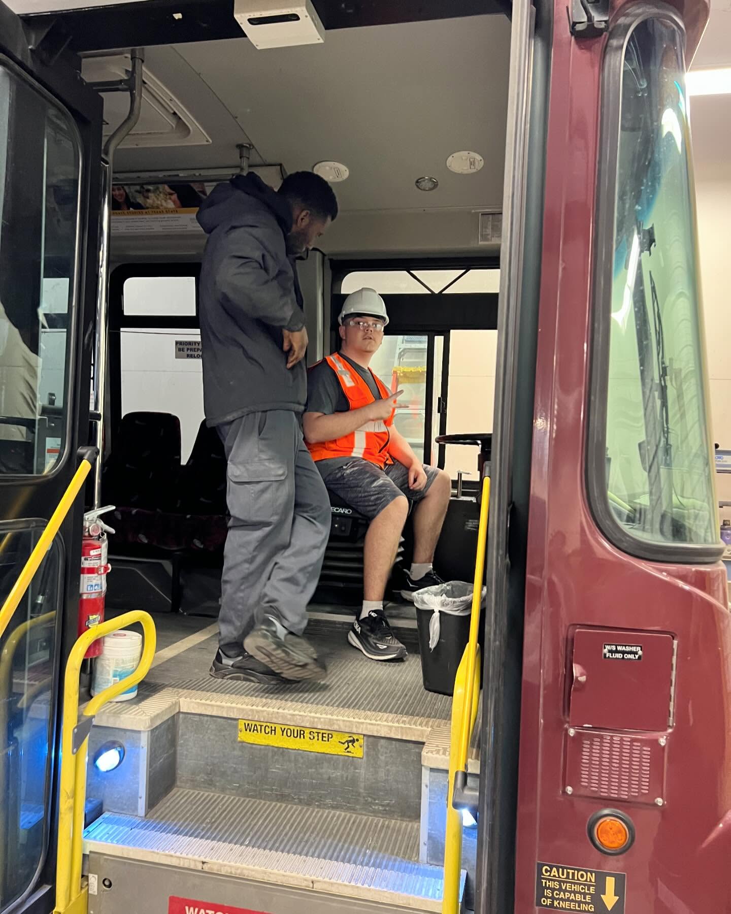 two men inside the front of a large shuttle bus