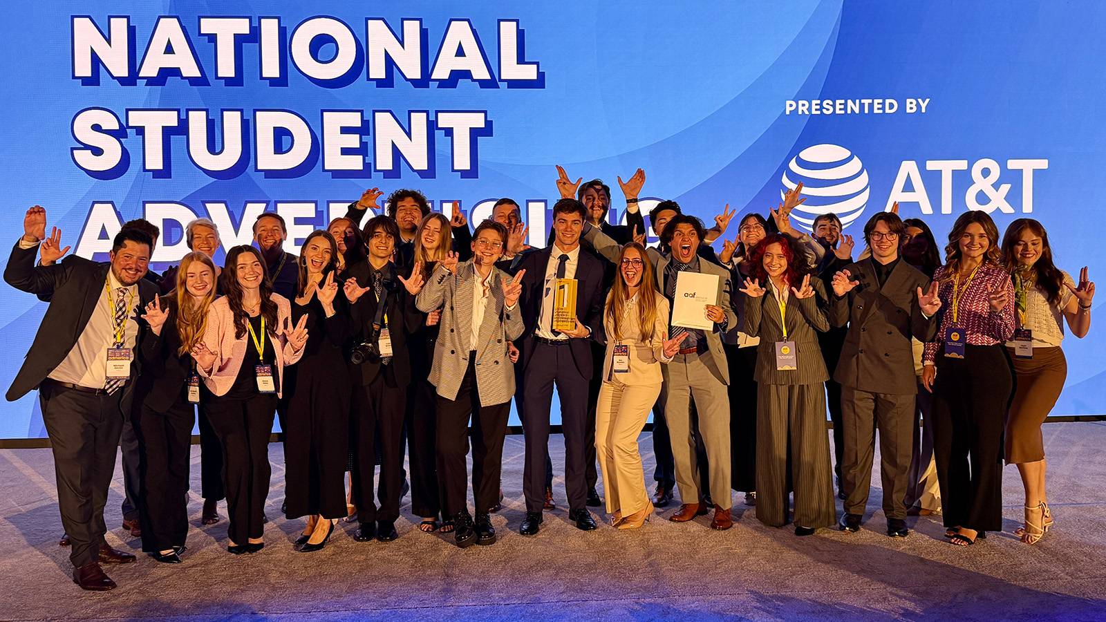 group of professionally dressed students posing on stage for photo