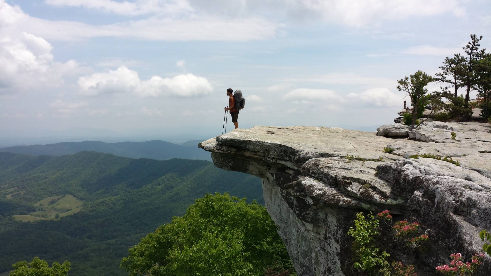 Landauer gazes out at the scenery at the edge of a rocky ledge on a desolate portion of the Appalachian Trail. Lush mountains sprawl beneath him.