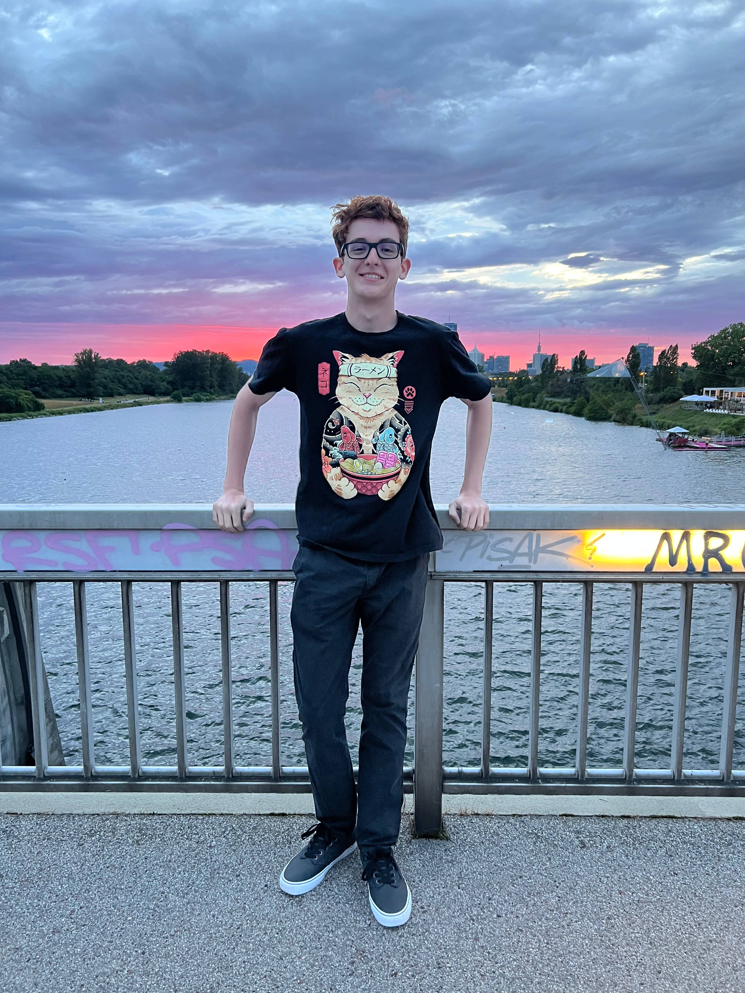Trace stands in front of a body of water on a bridge. 