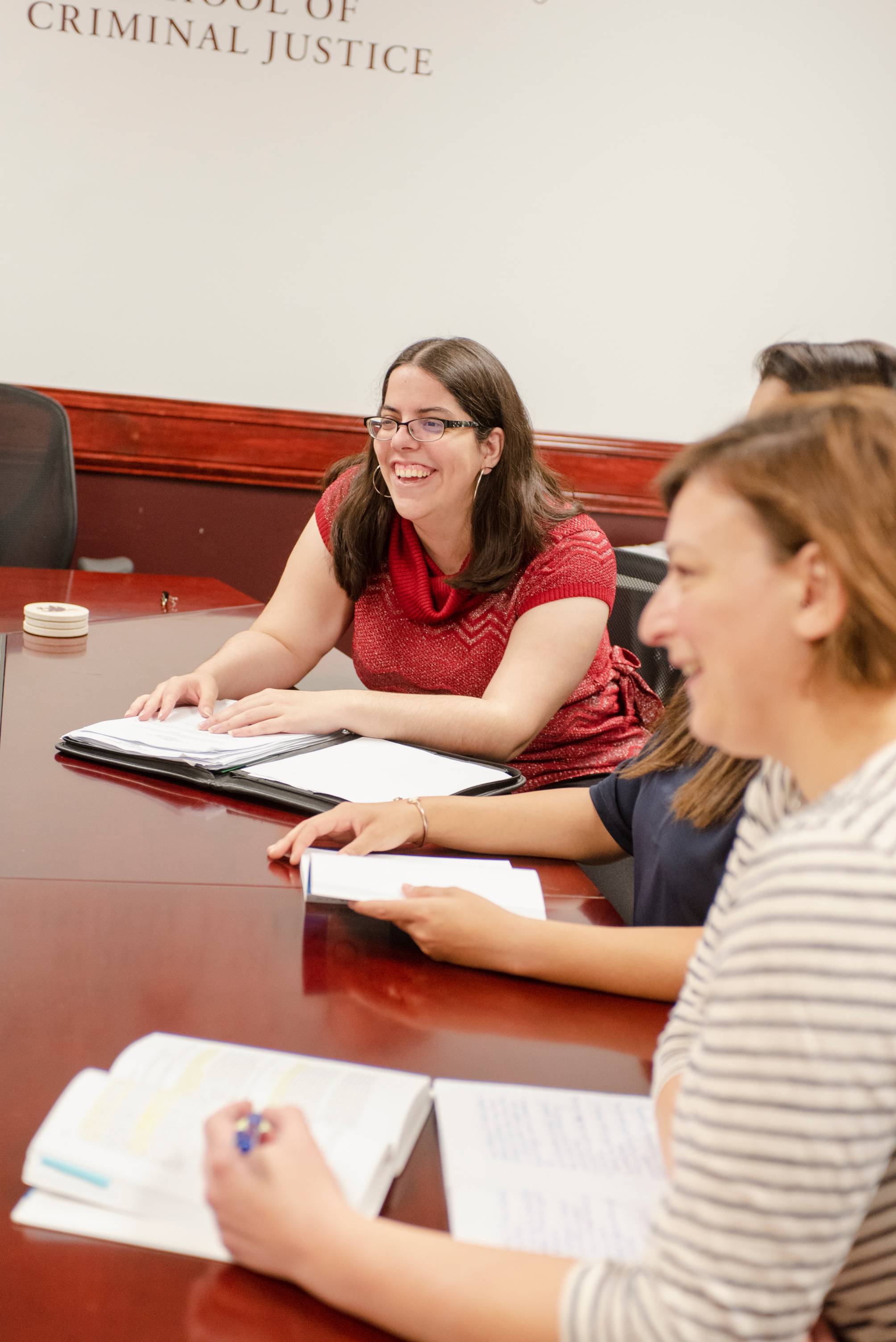 Faculty at a conference table laughing