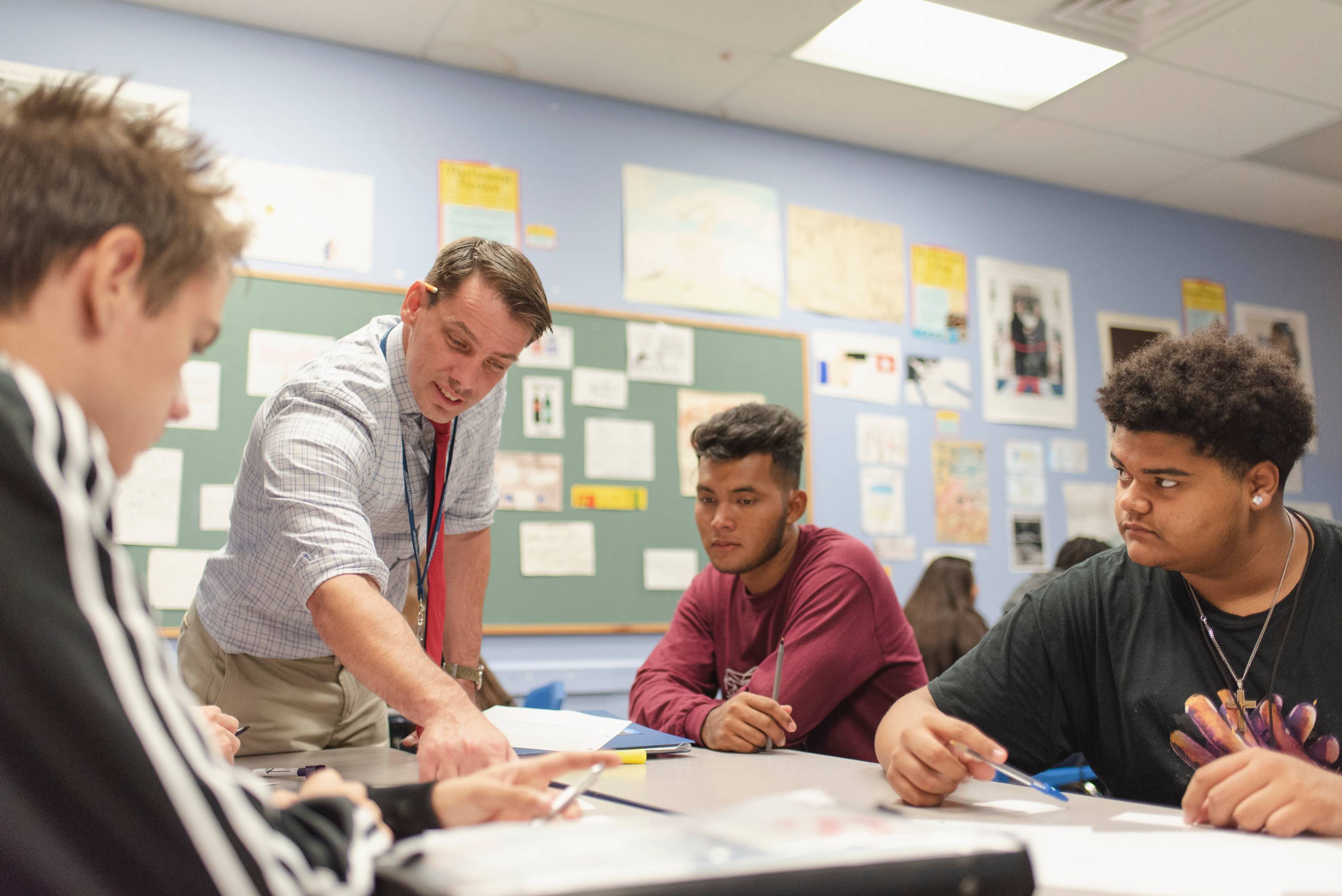 Professor at a table full of students teaching.