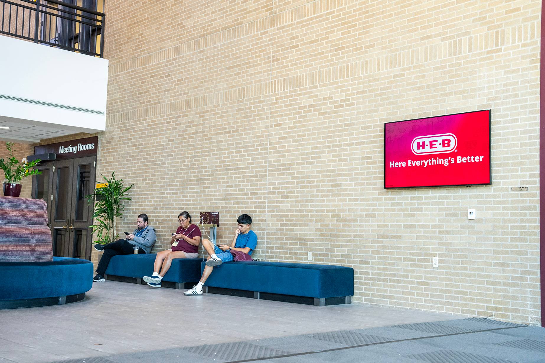 digital display board on wall above sofa with students sitting on it