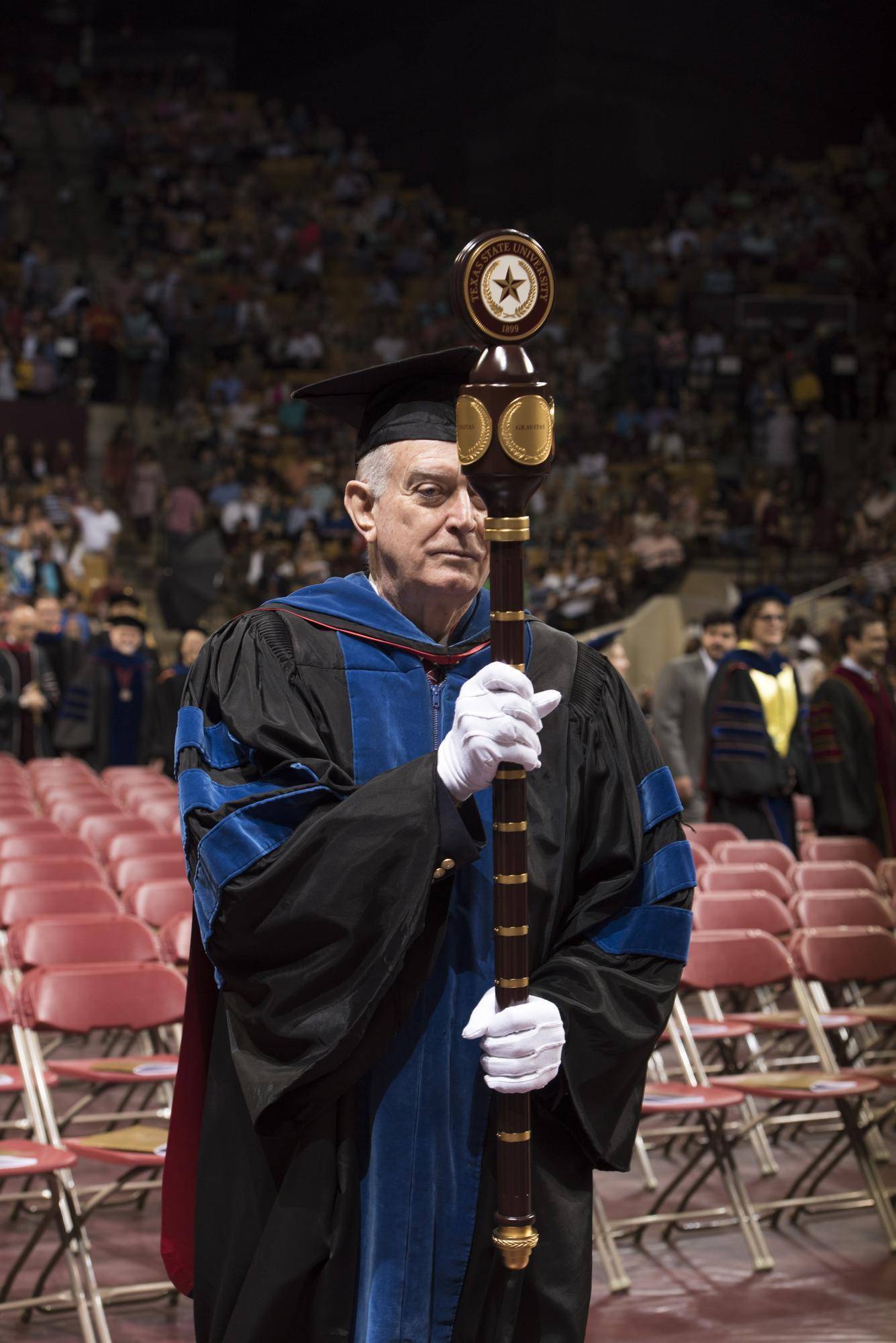 faculty member carrying in the ceremonial mace during commencement ceremony