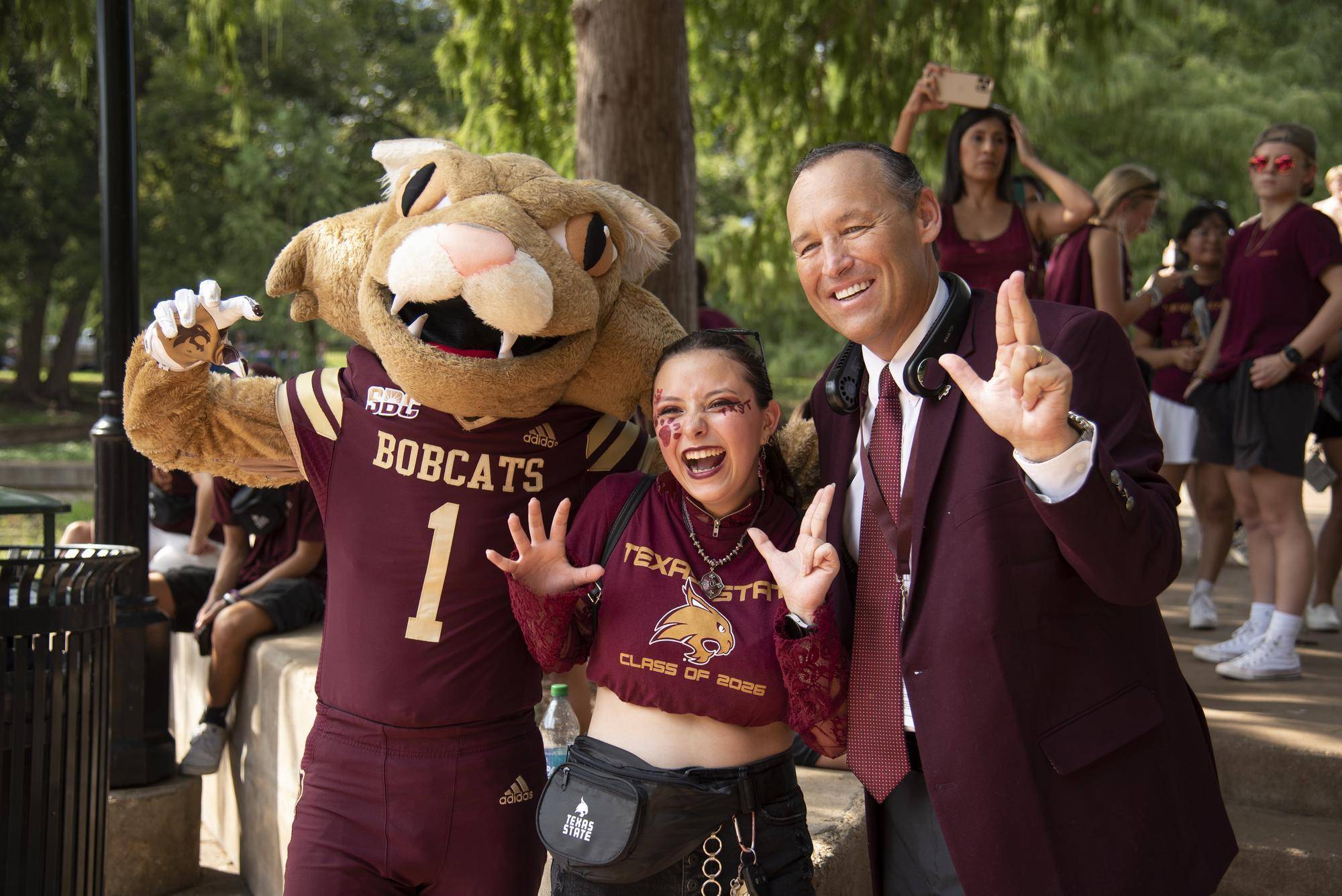 mascot, woman and president damphousse holding up txst hand signs